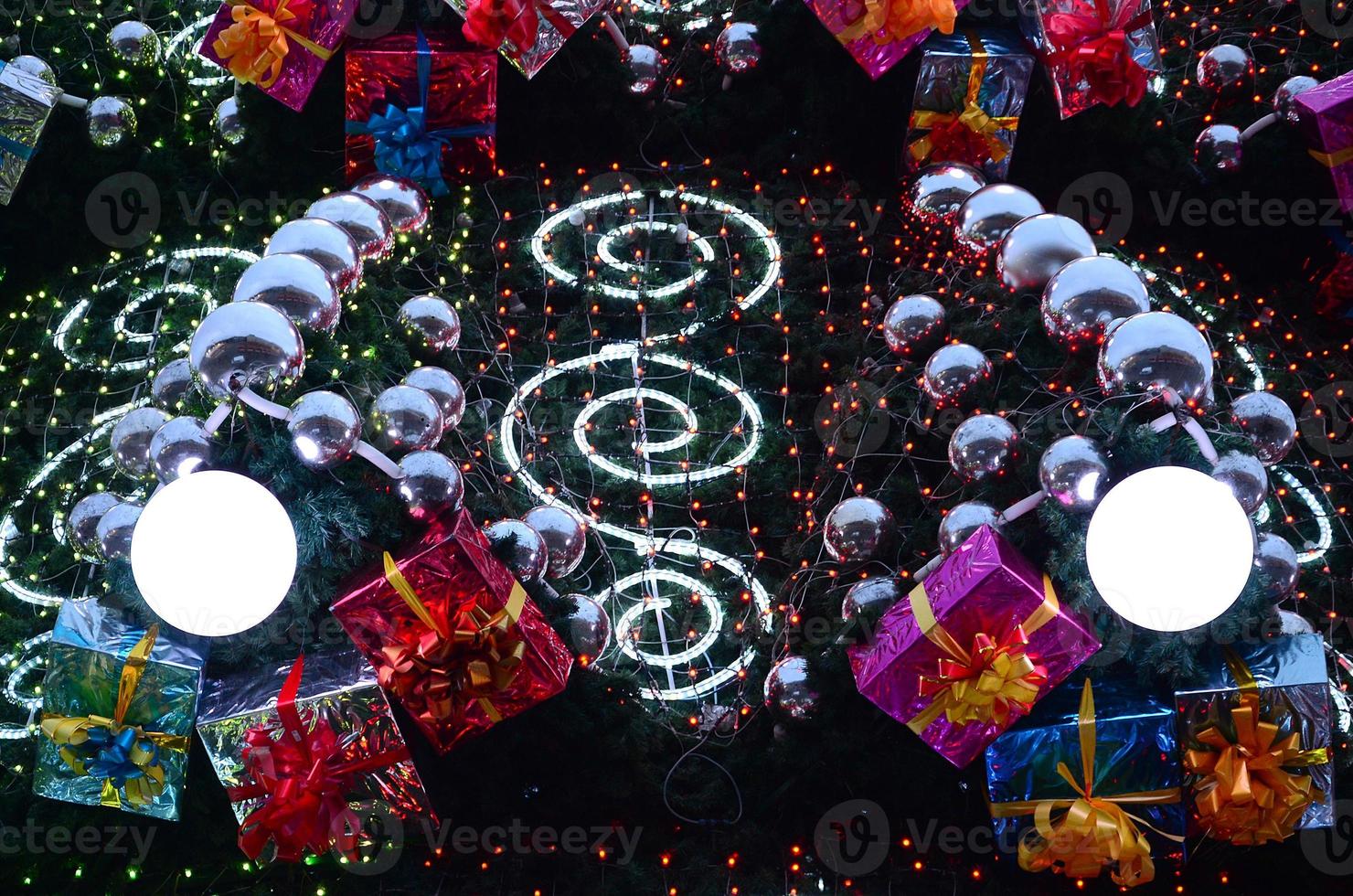 um fragmento de uma enorme árvore de natal com muitos enfeites, caixas de presente e lâmpadas luminosas. foto de uma árvore de natal decorada close-up