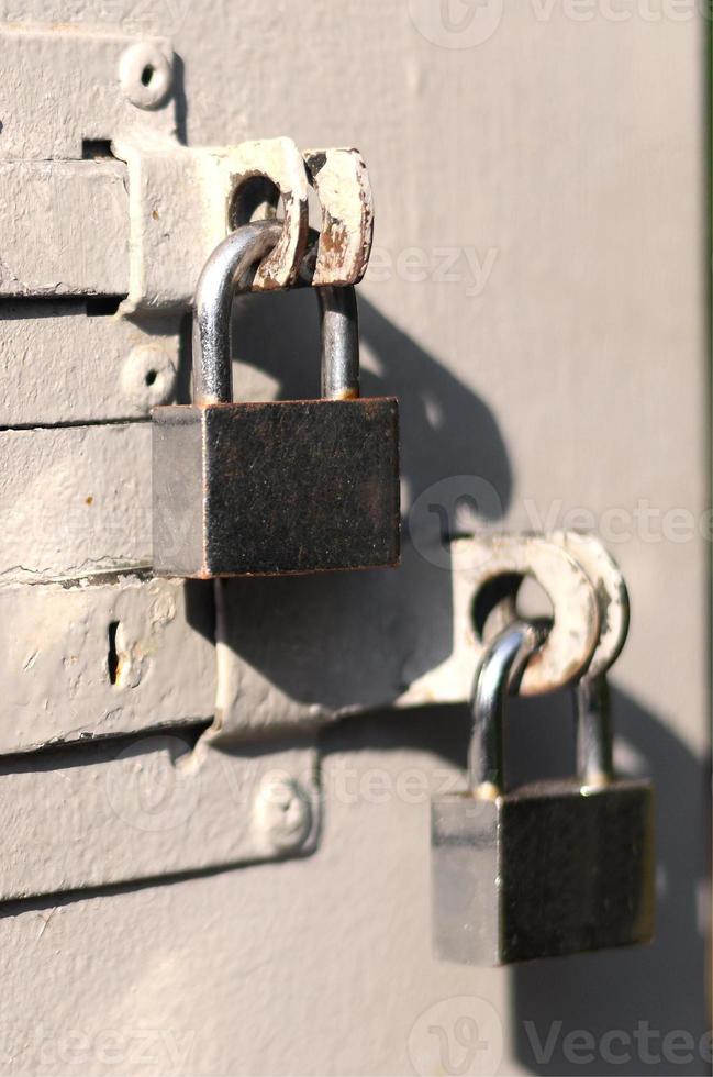 uma fotografia do fragmento é uma porta de metal com dois cadeados quadrados. foco seletivo com profundidade de campo rasa foto