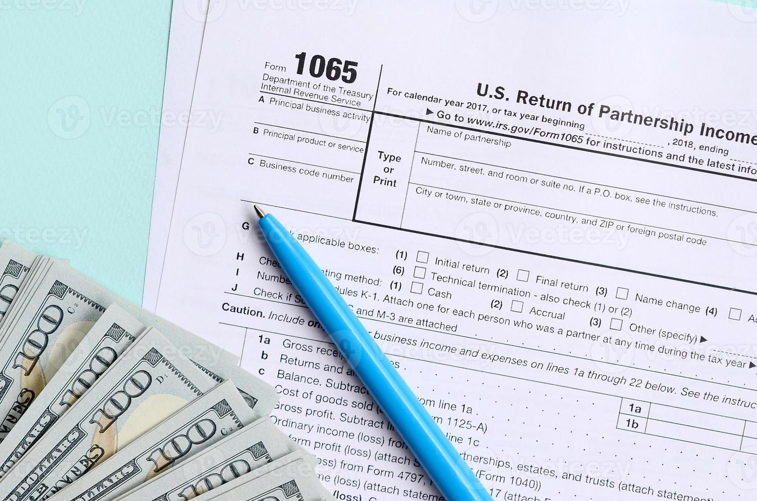 1065 formulário de imposto fica perto de notas de cem dólares e caneta azul sobre um fundo azul claro. nos devolvemos para renda de paternidade foto