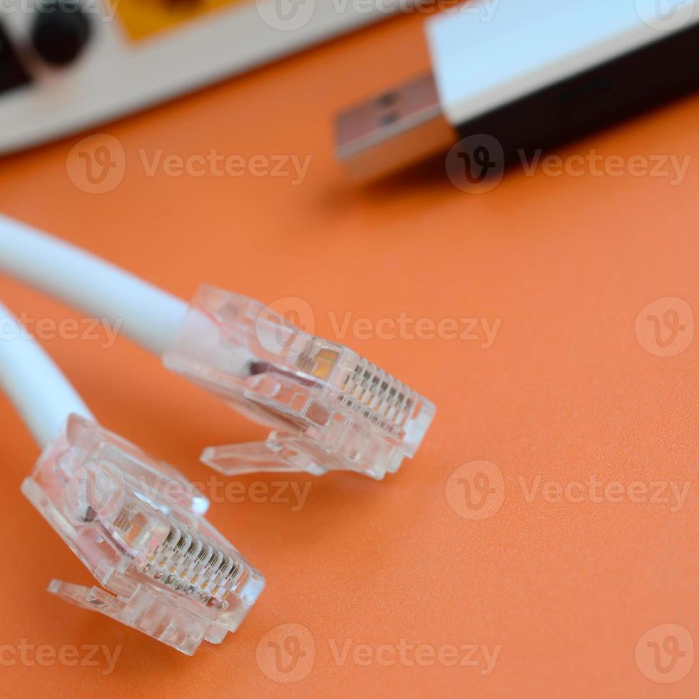 roteador de internet, adaptador wi-fi usb portátil e plugues de cabo de internet estão em um fundo laranja brilhante. itens necessários para conexão com a internet foto