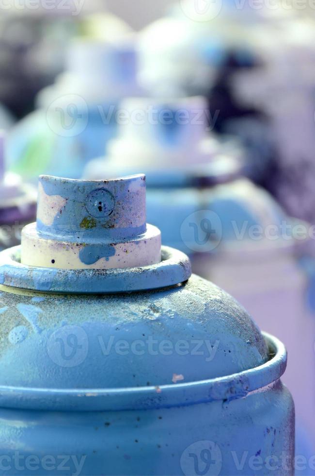 muitas latas de aerossol sujas e usadas de tinta azul brilhante. fotografia macro com profundidade de campo rasa. foco seletivo no bico de pulverização foto