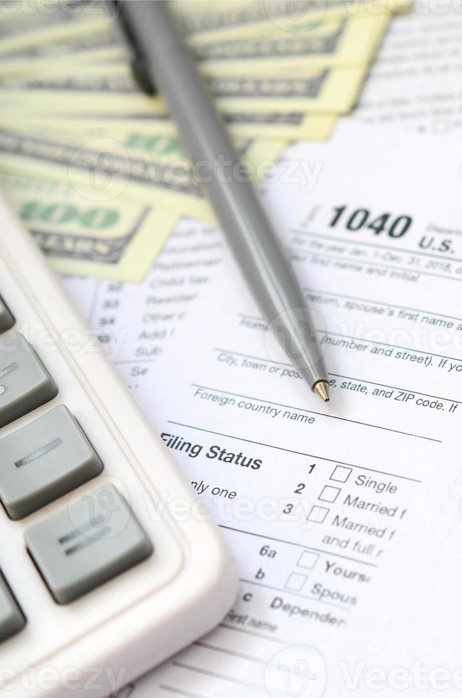 a caneta, o caderno, a calculadora e as notas de dólar estão na declaração de imposto de renda individual 1040 us. hora de pagar impostos foto
