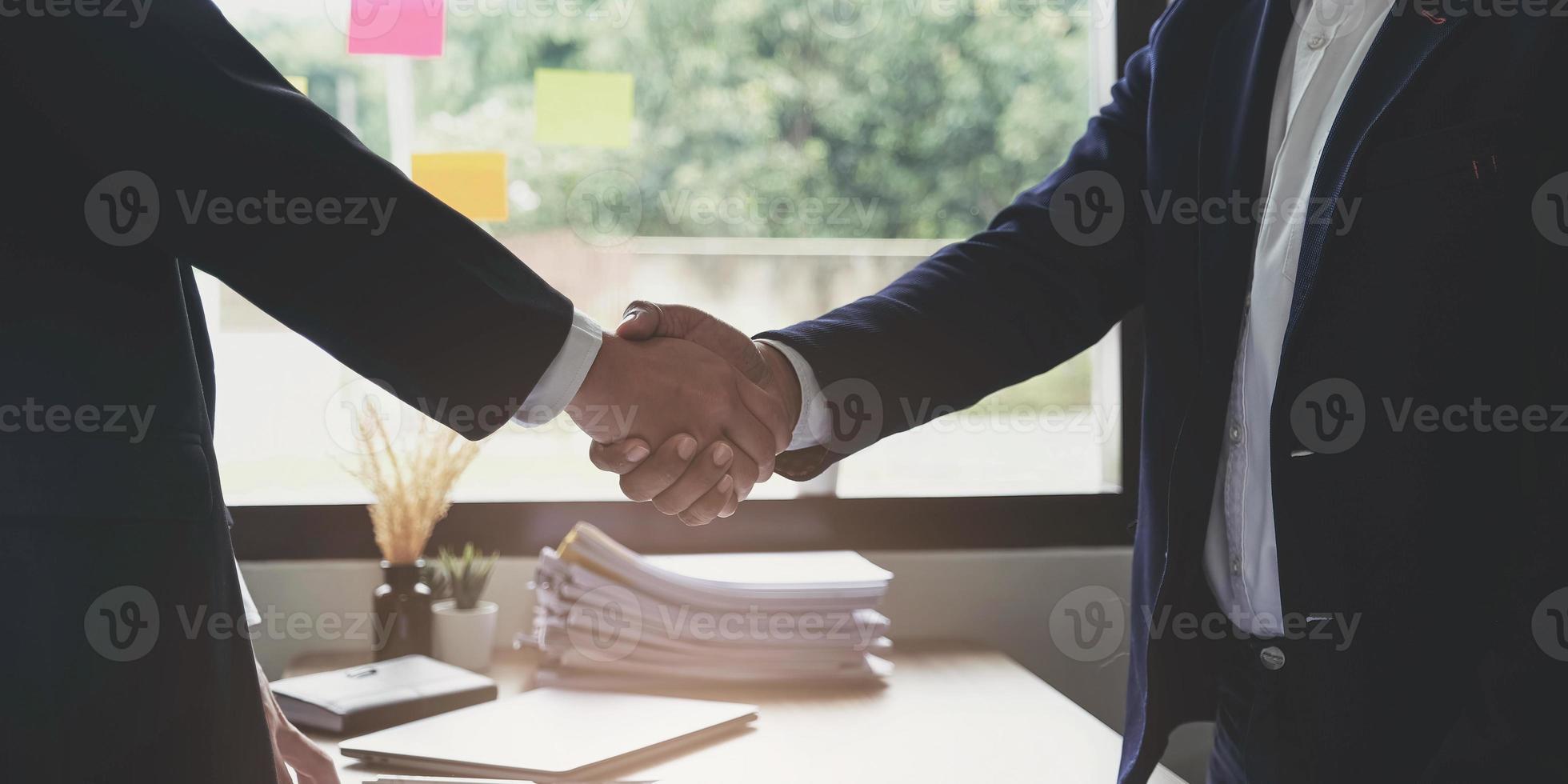 dois confiante homem de negócios apertando as mãos durante uma reunião no conceito de escritório, sucesso, tratamento, saudação e parceiro. foto