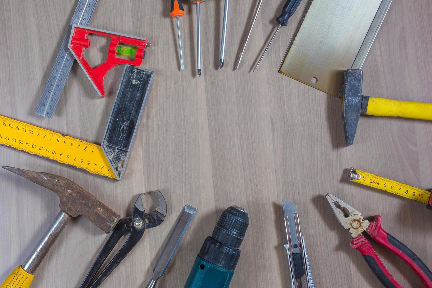 ferramentas diferentes em um fundo de madeira. martelo, furadeira, alicate. chave de fenda, régua, alicate de corte foto