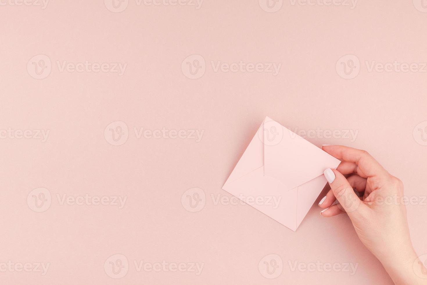 mão de mulher segurando uma pequena carta de amor rosa foto