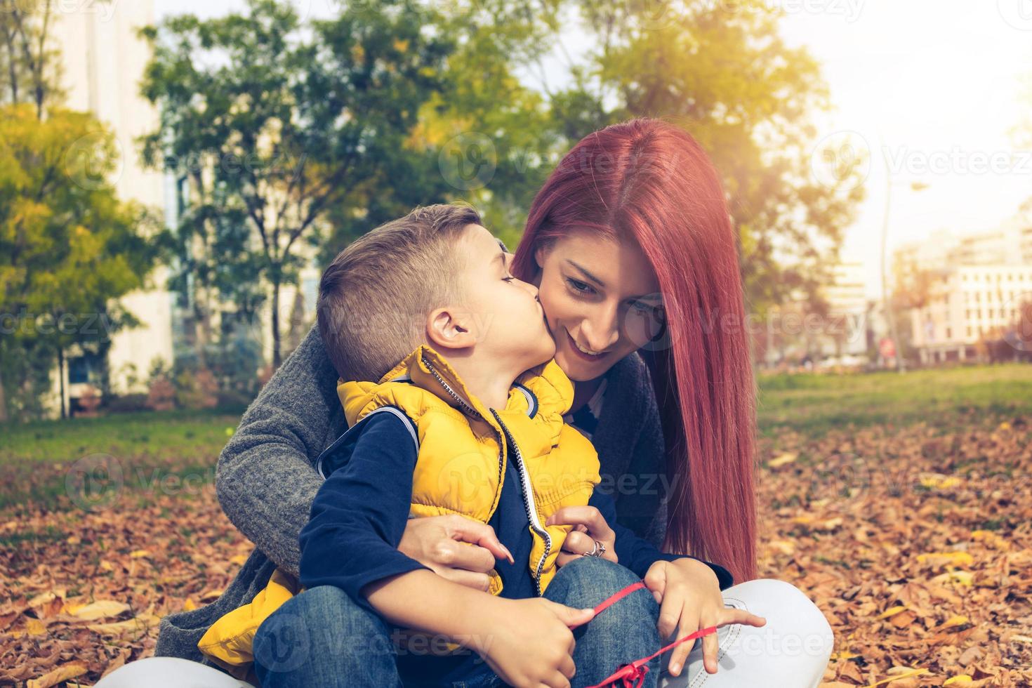 filho pequeno beijando sua mãe na bochecha. foto