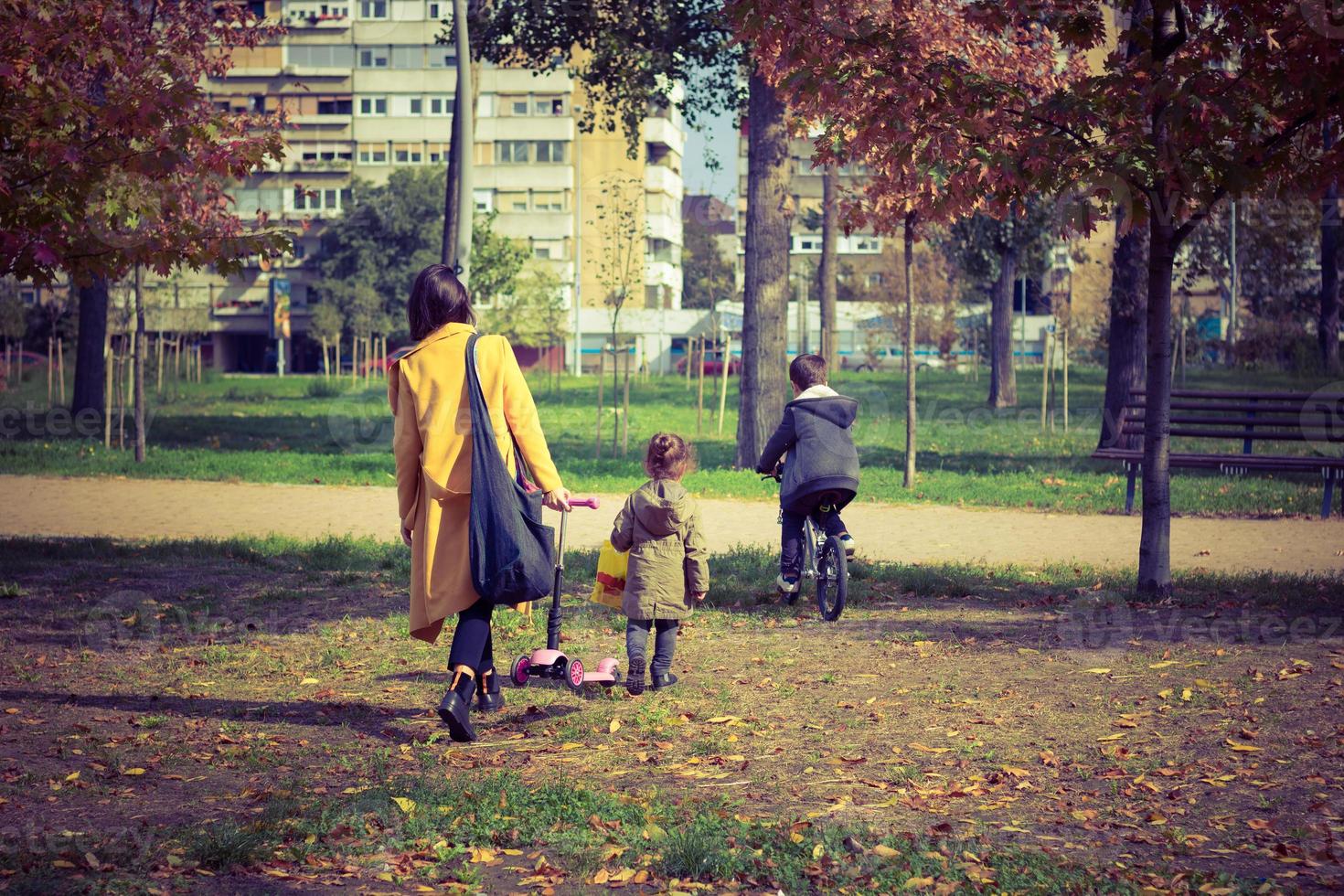 vista traseira da mãe e filhos andando pelo parque. foto