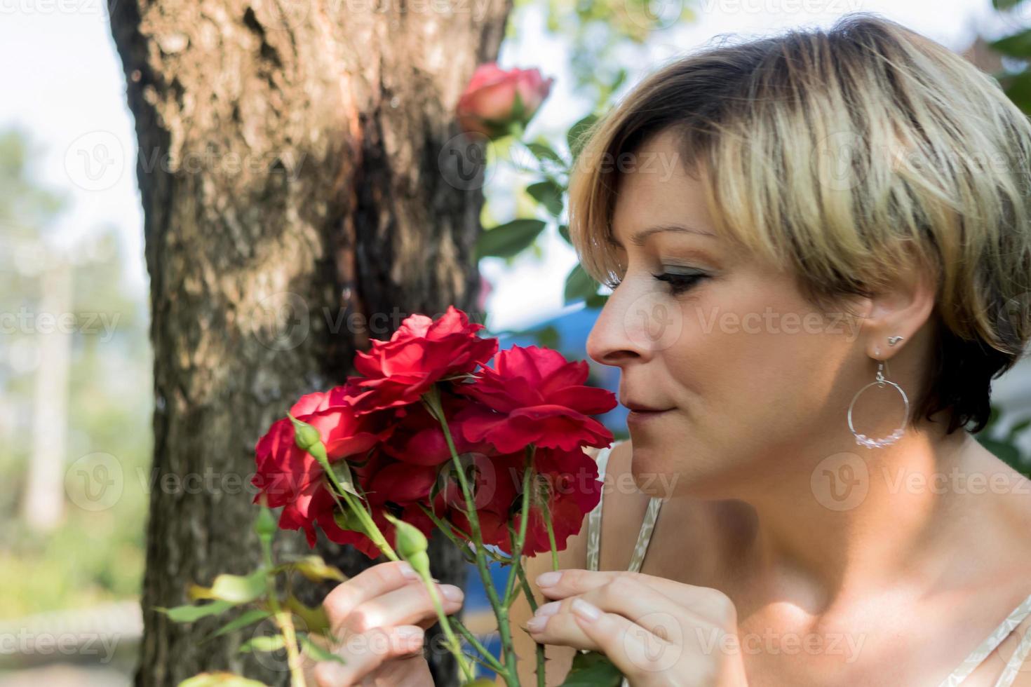 mulher adulta mediana cheirando rosas vermelhas. foto