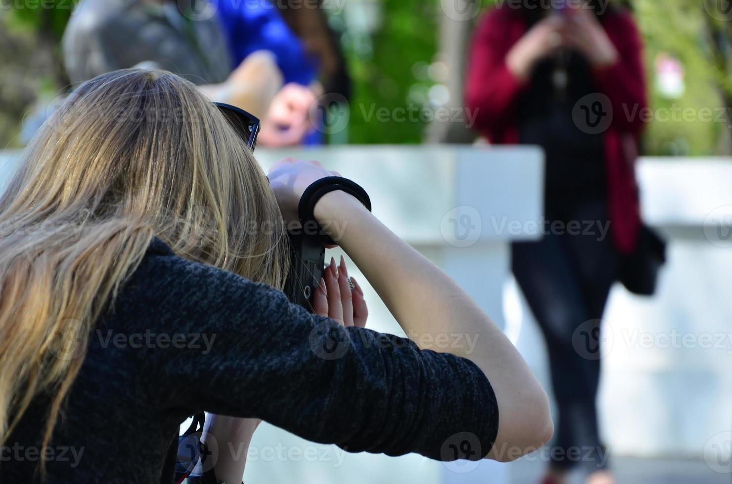 fotógrafo de casamento no processo de seu trabalho. fotógrafo profissional atira uma cerimônia de casamento. uma jovem olha para o visor da câmera foto