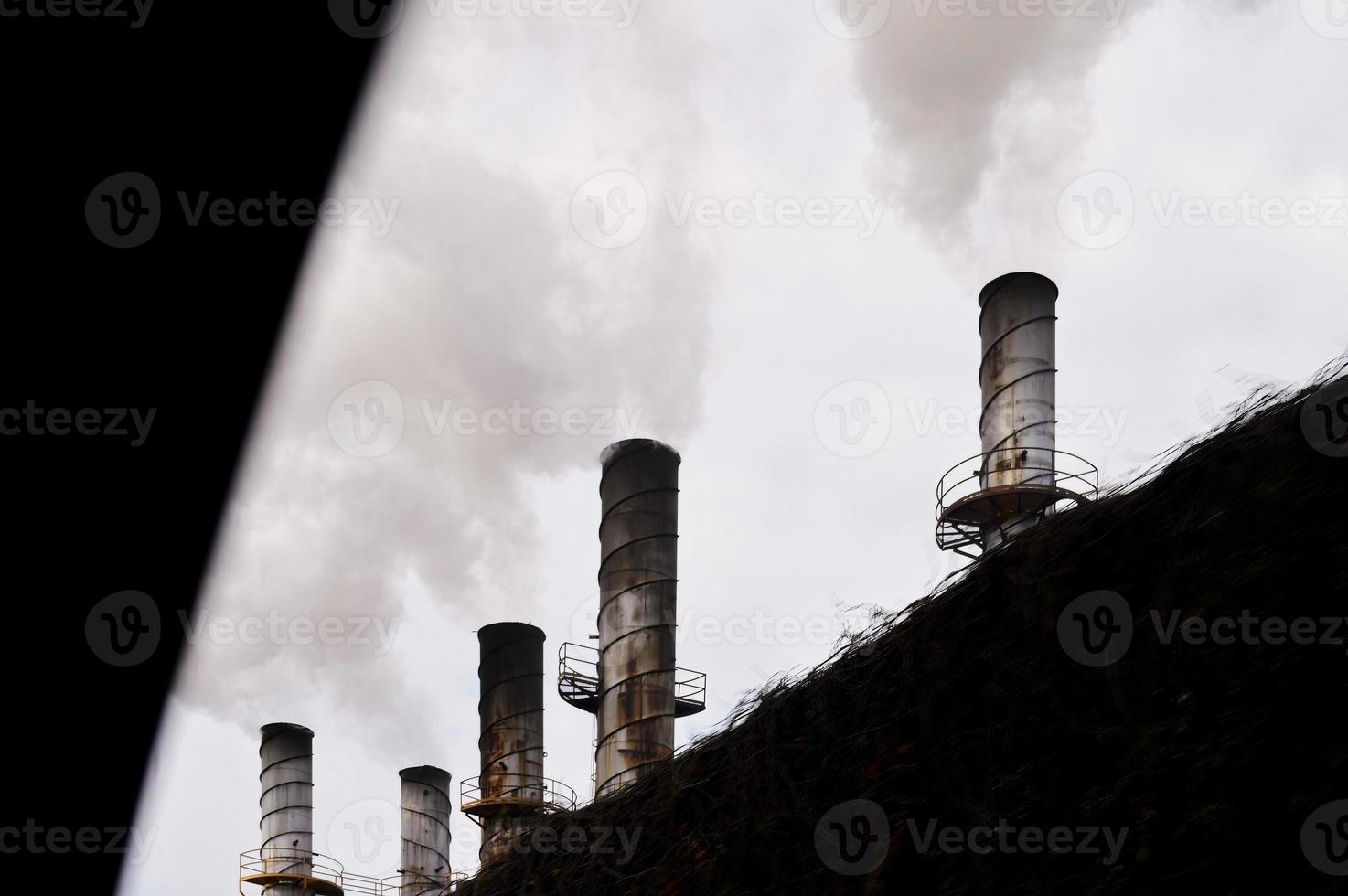 chaminés industriais expelindo fumaça poluindo atrás de uma cerca foto