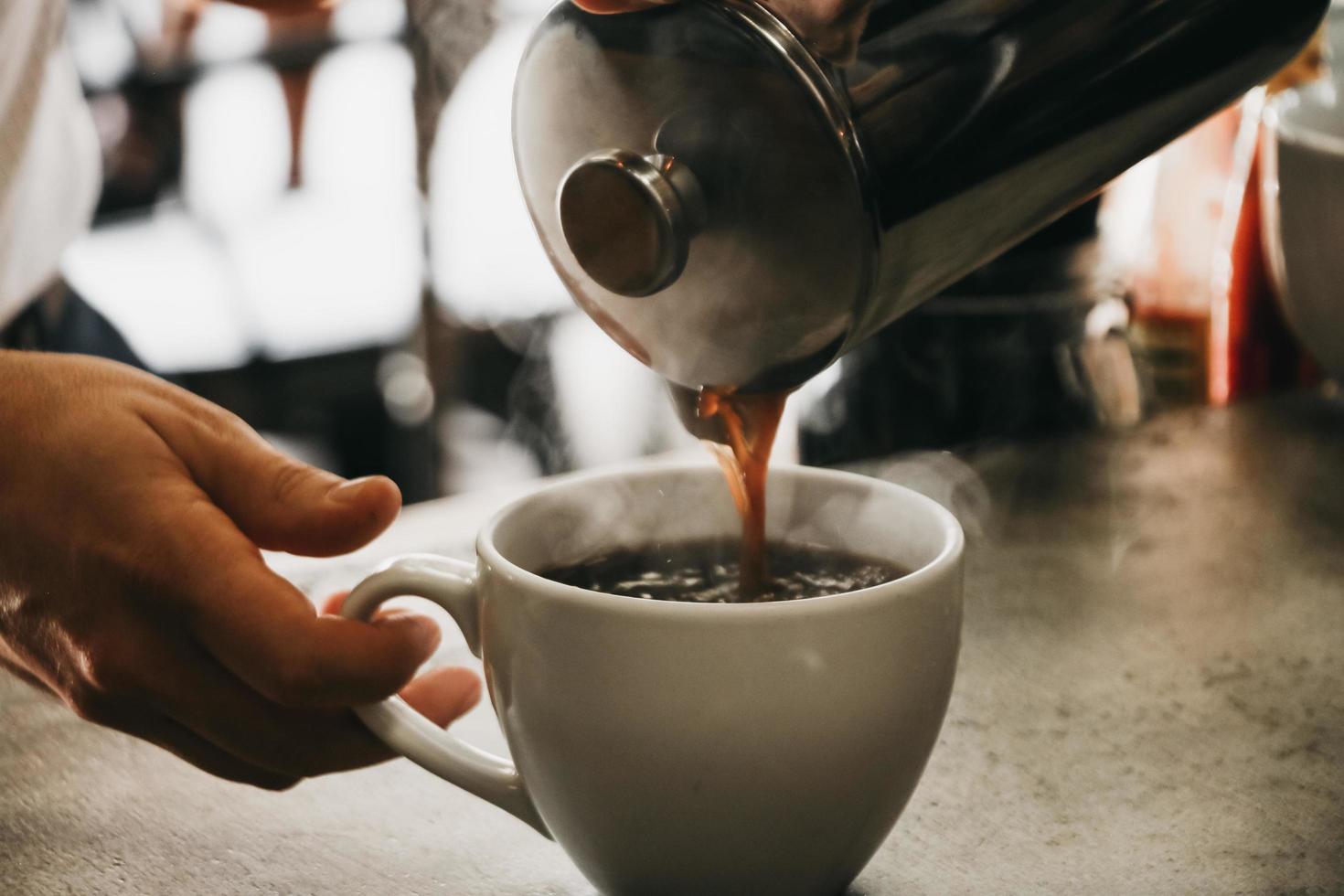 pessoa servindo café em xícara de cerâmica branca foto