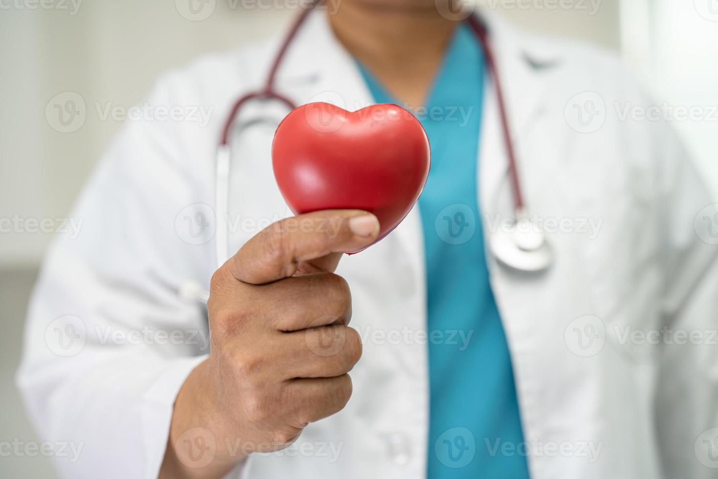 médico segurando um coração vermelho na enfermaria do hospital, conceito médico forte e saudável. foto