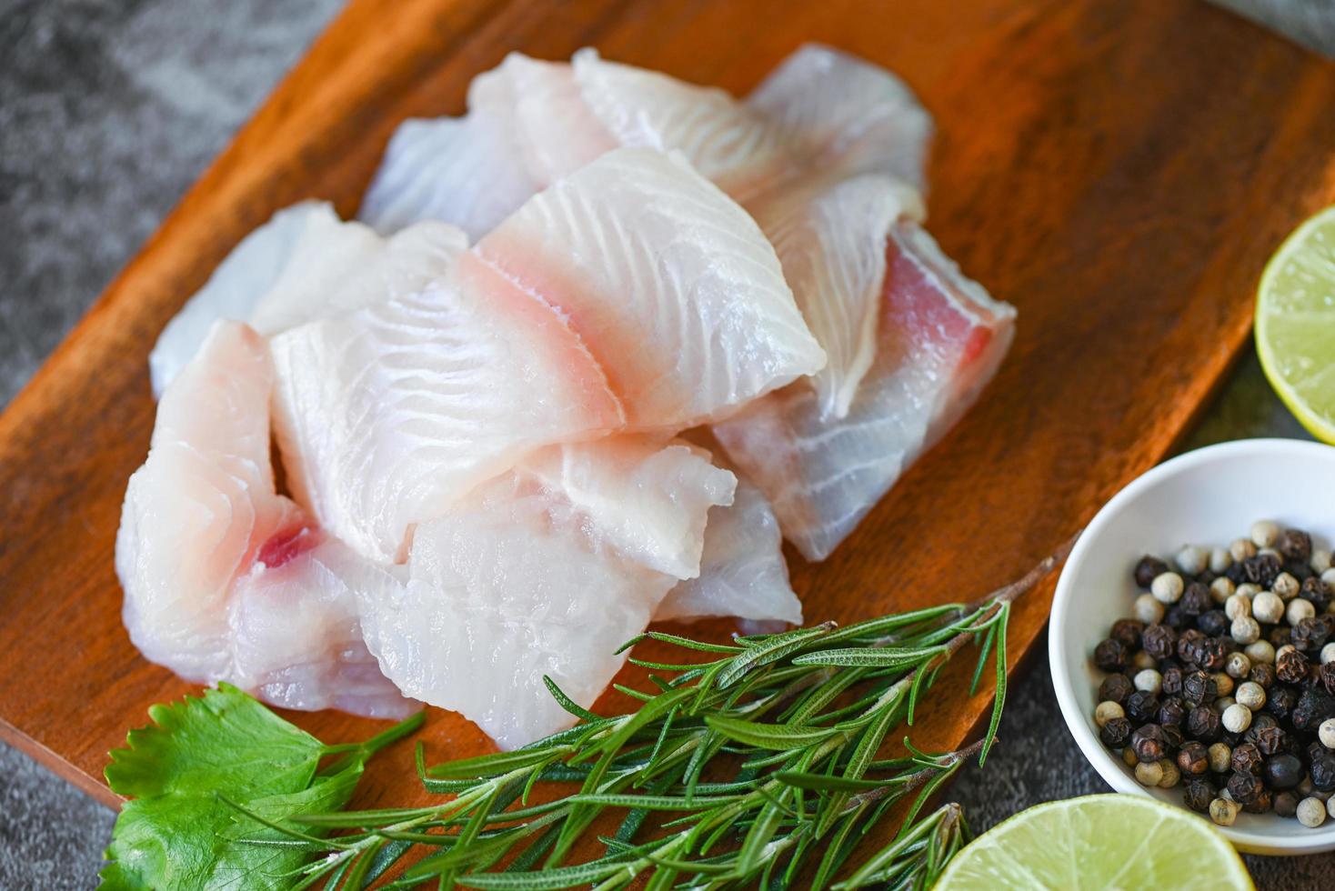 filé de peixe pangasius cru fresco com, carne dolly peixe tilápia listrado peixe-gato, filé de peixe na placa de madeira com ingredientes aipo para cozinhar foto