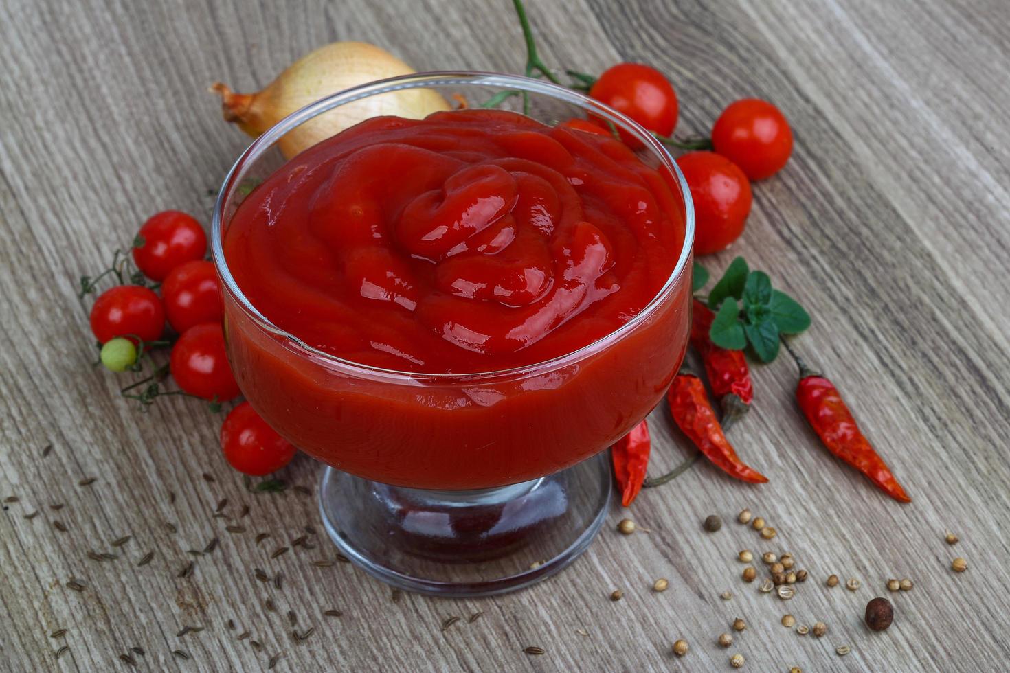 ketchup de tomate em uma tigela no fundo de madeira foto