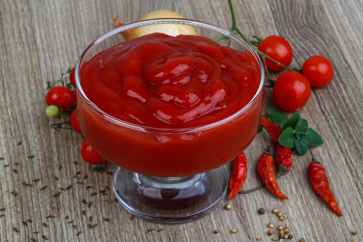 ketchup de tomate em uma tigela no fundo de madeira foto