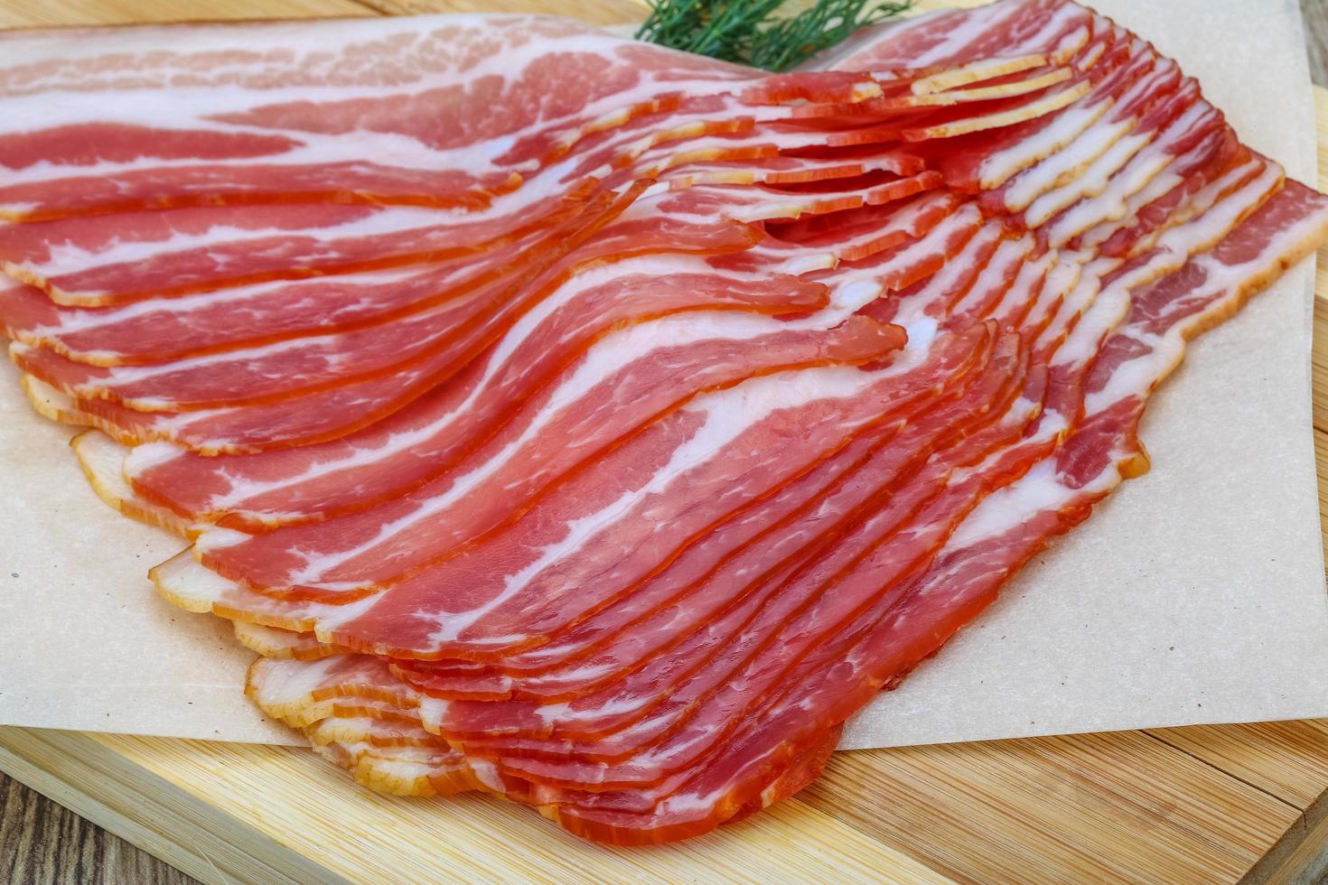 bacon fatiado na placa de madeira e fundo de madeira foto