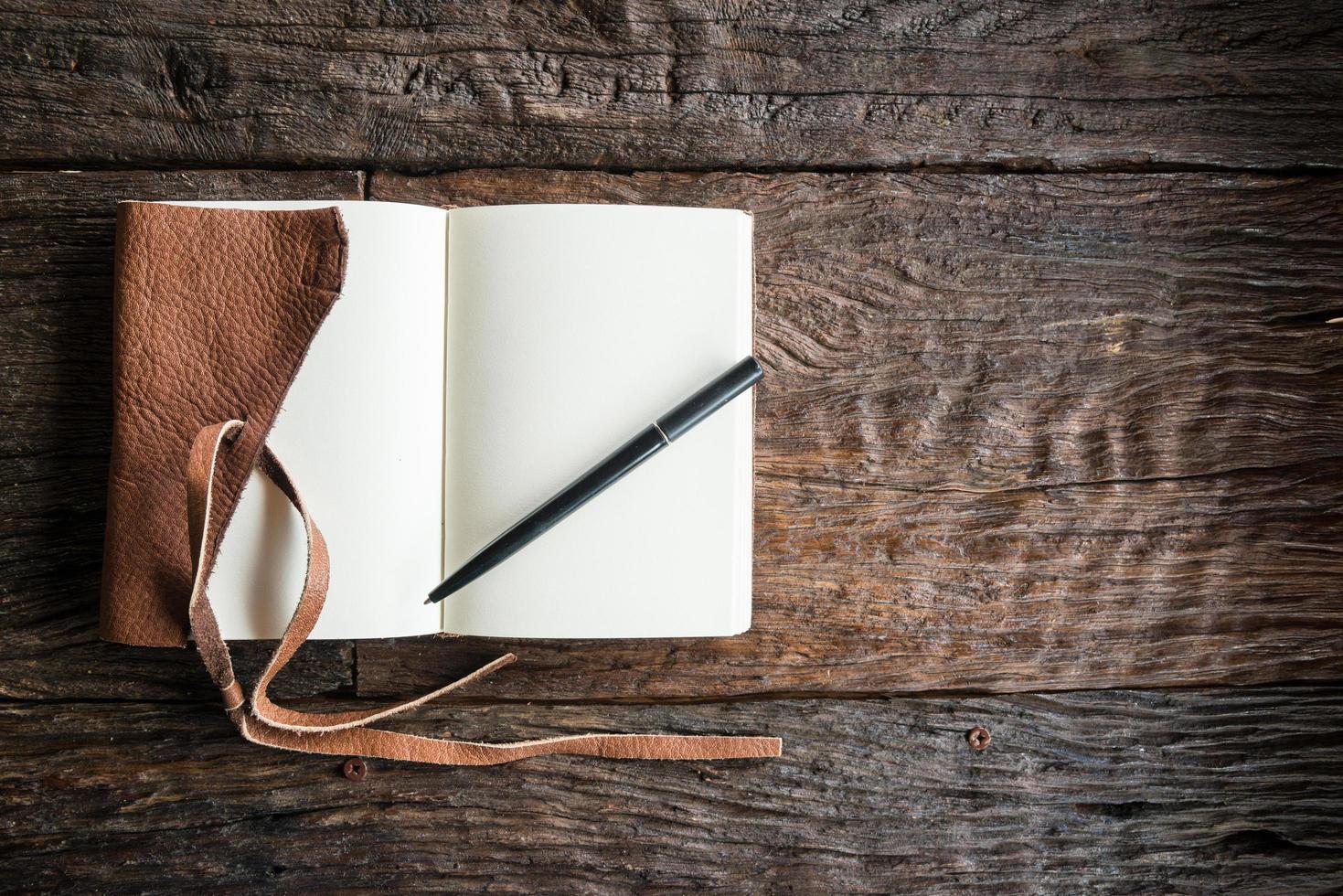 um livro de couro diário aberto com espaço em branco na mesa de madeira. o conceito de educação e aprendizagem. foto