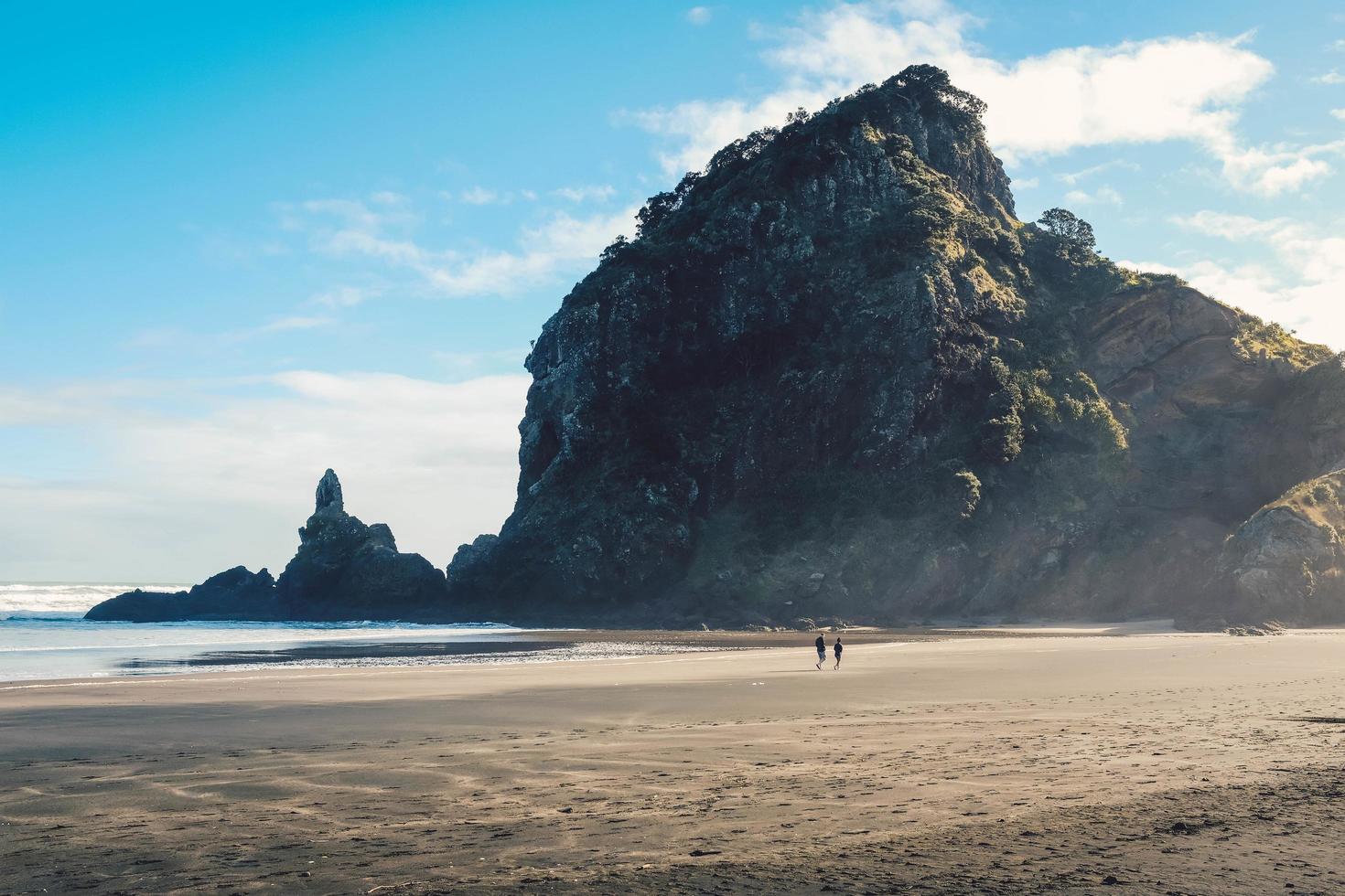 duas pessoas na praia perto da montanha foto