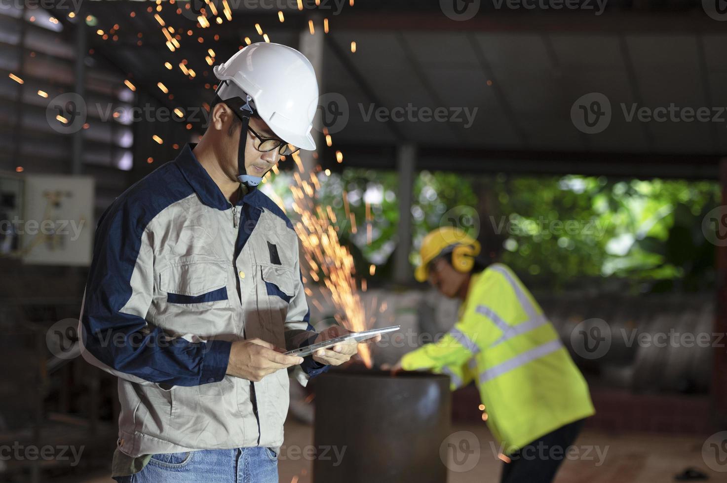 trabalhadores asiáticos, engenheiros profissionais da indústria pesada vestindo roupas de segurança e capacetes, usam computadores tablet. profissionais da indústria asiática estão em plantas metalúrgicas. foto