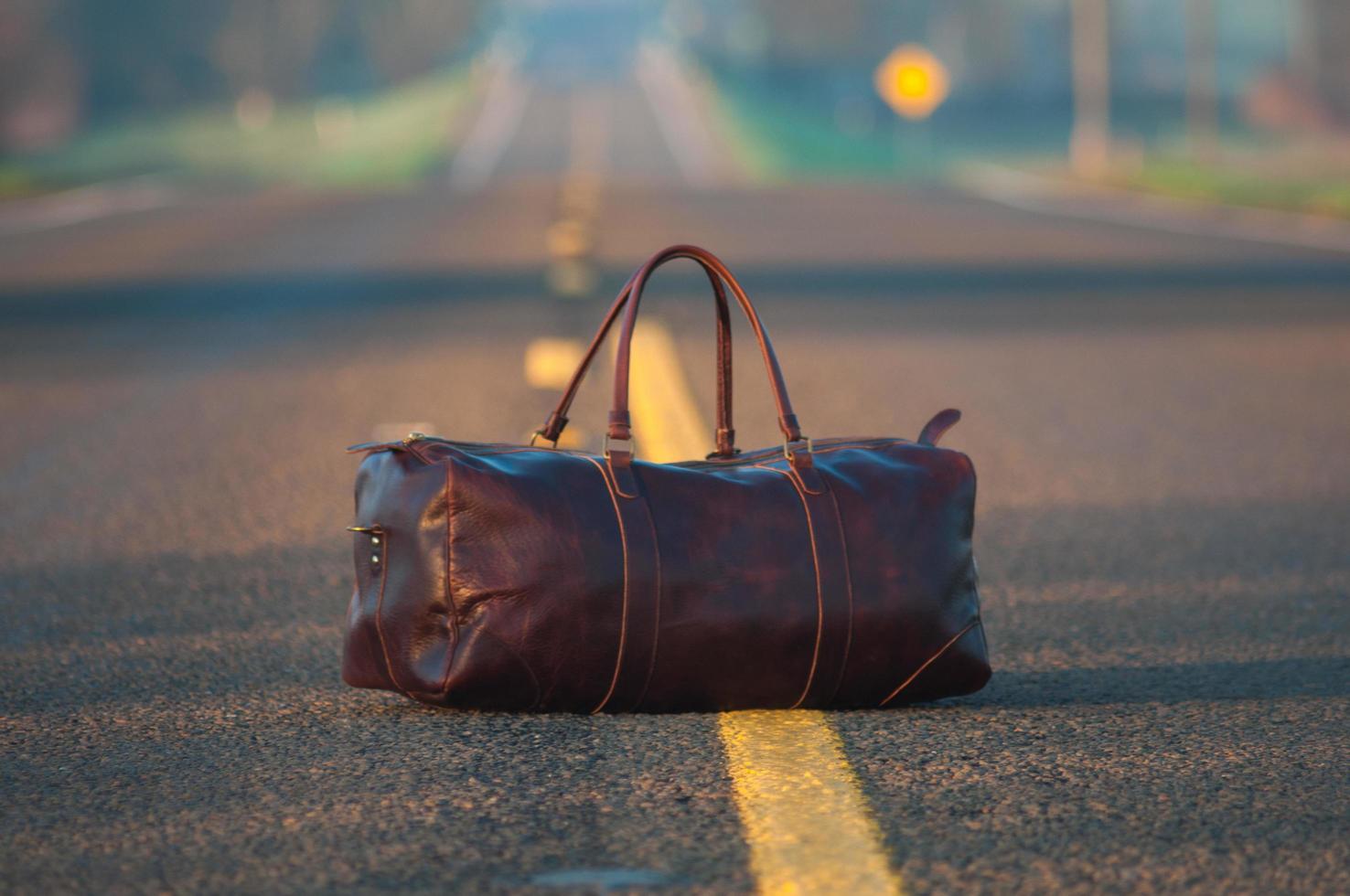 mochila de couro marrom no meio da estrada de asfalto foto