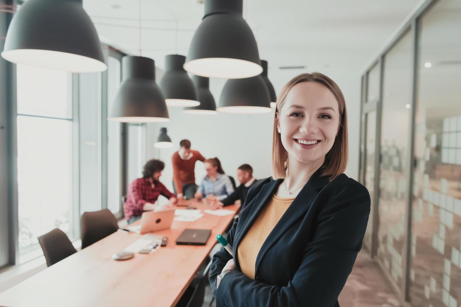 retrato de proprietário de empresária feliz no escritório moderno. empresária sorrindo e olhando para a câmera. equipe diversificada ocupada trabalhando em segundo plano. conceito de liderança. Tiros na Cabeça. foto