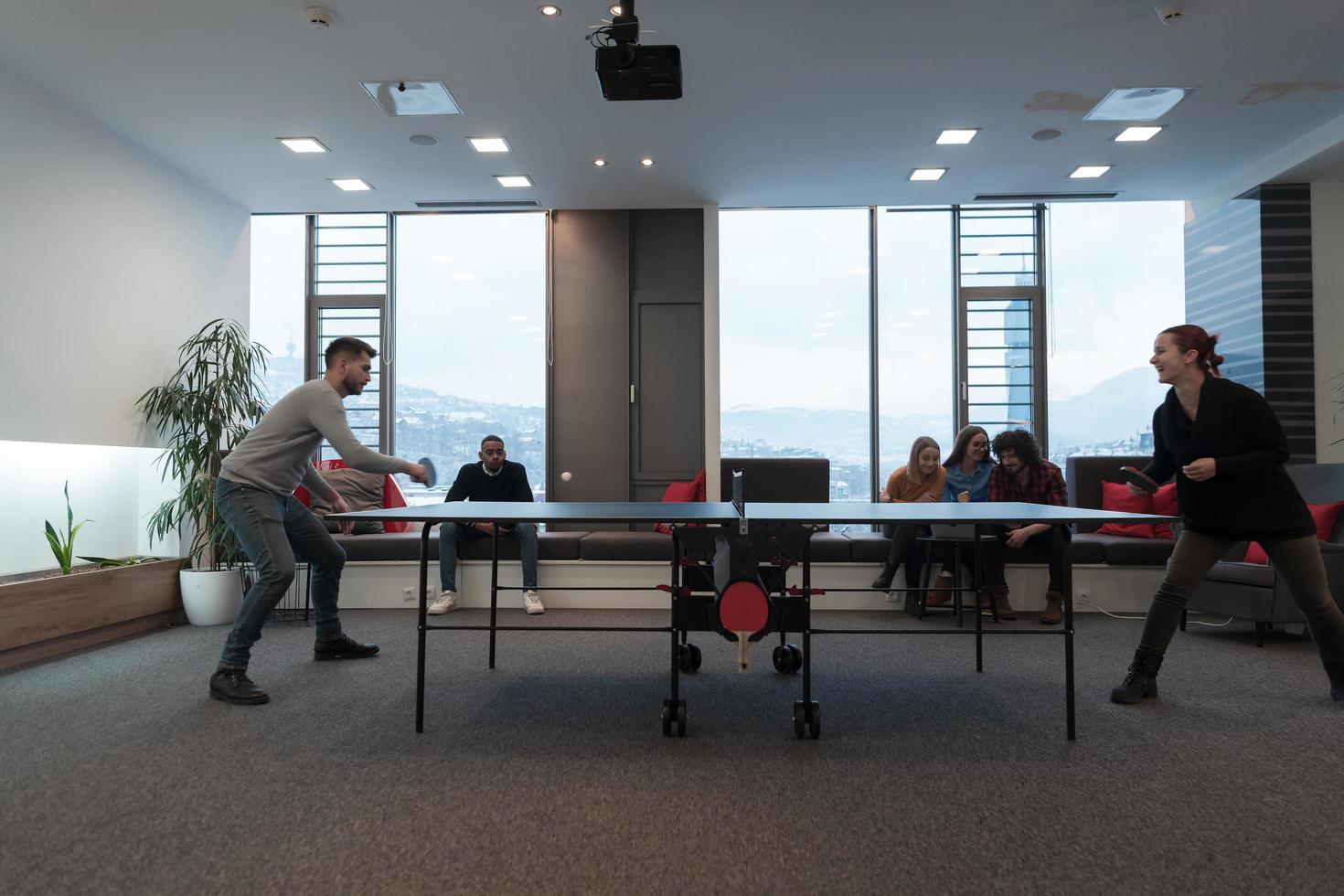 jovem iniciante homem de negócios e mulher jogando tênis de mesa no espaço de escritório criativo moderno grupo de pessoas tem reunião e brainstorming em segundo plano foto