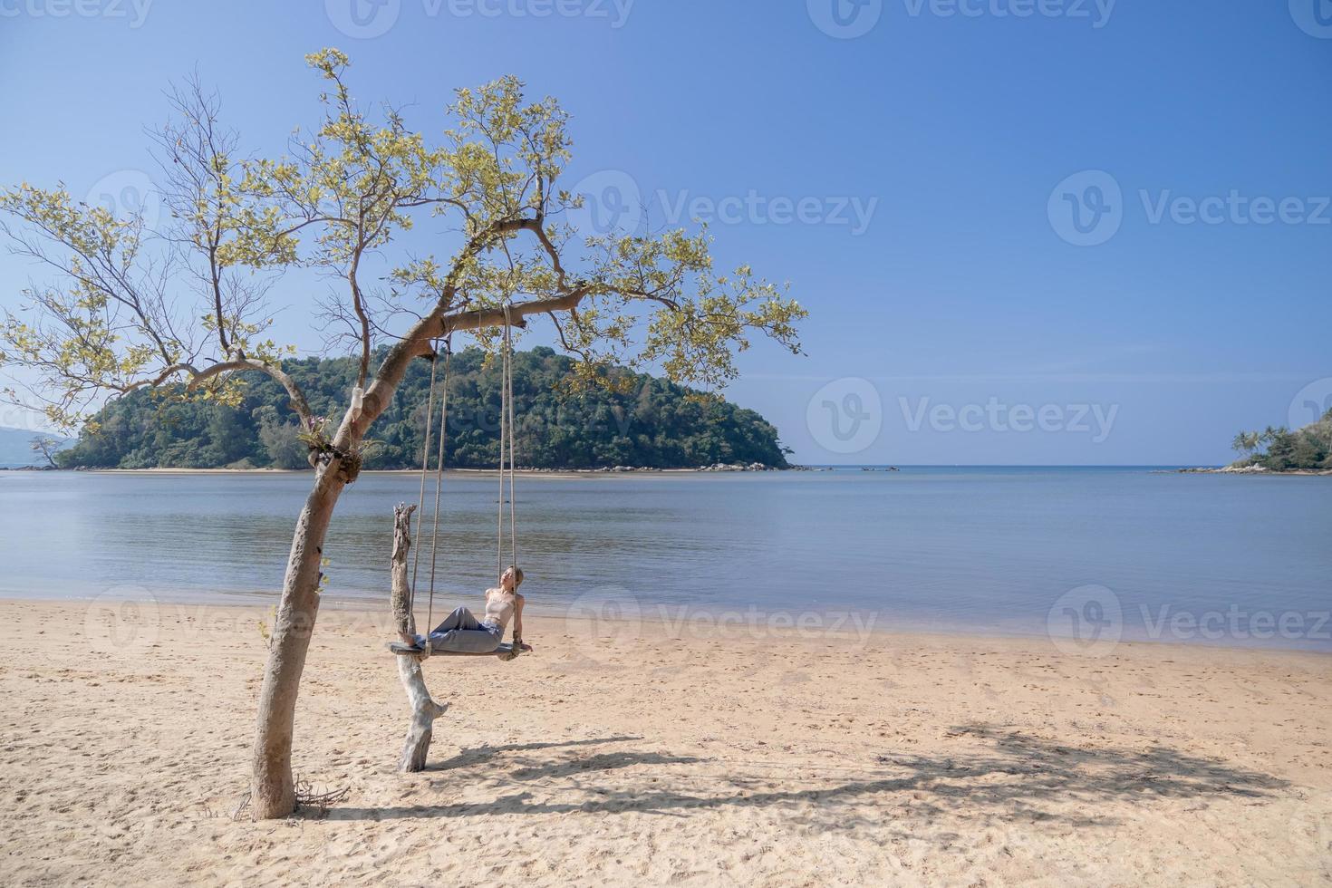 mulher sentada em um balanço, na praia. foto