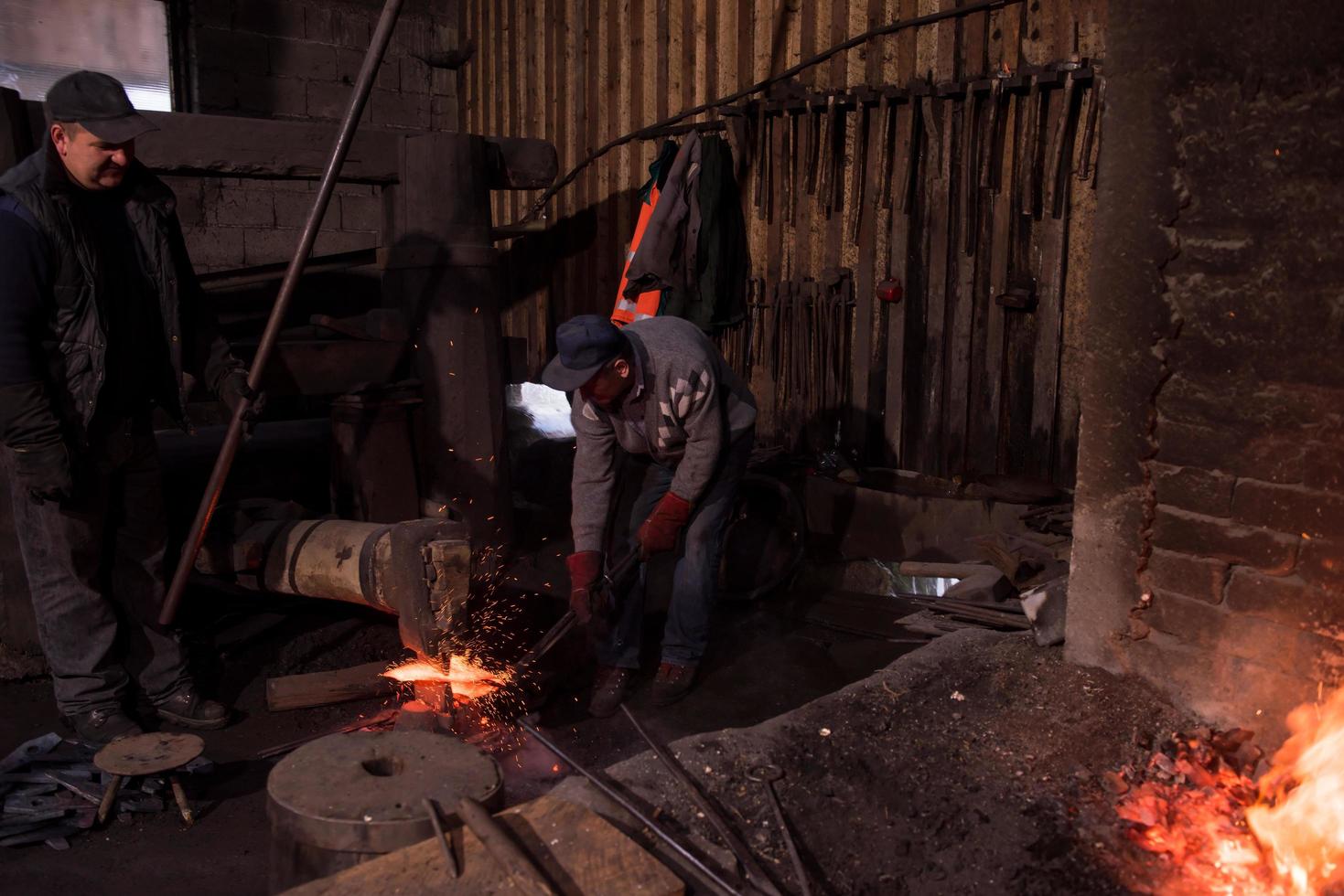 trabalhadores de ferreiro usando martelo mecânico na oficina foto