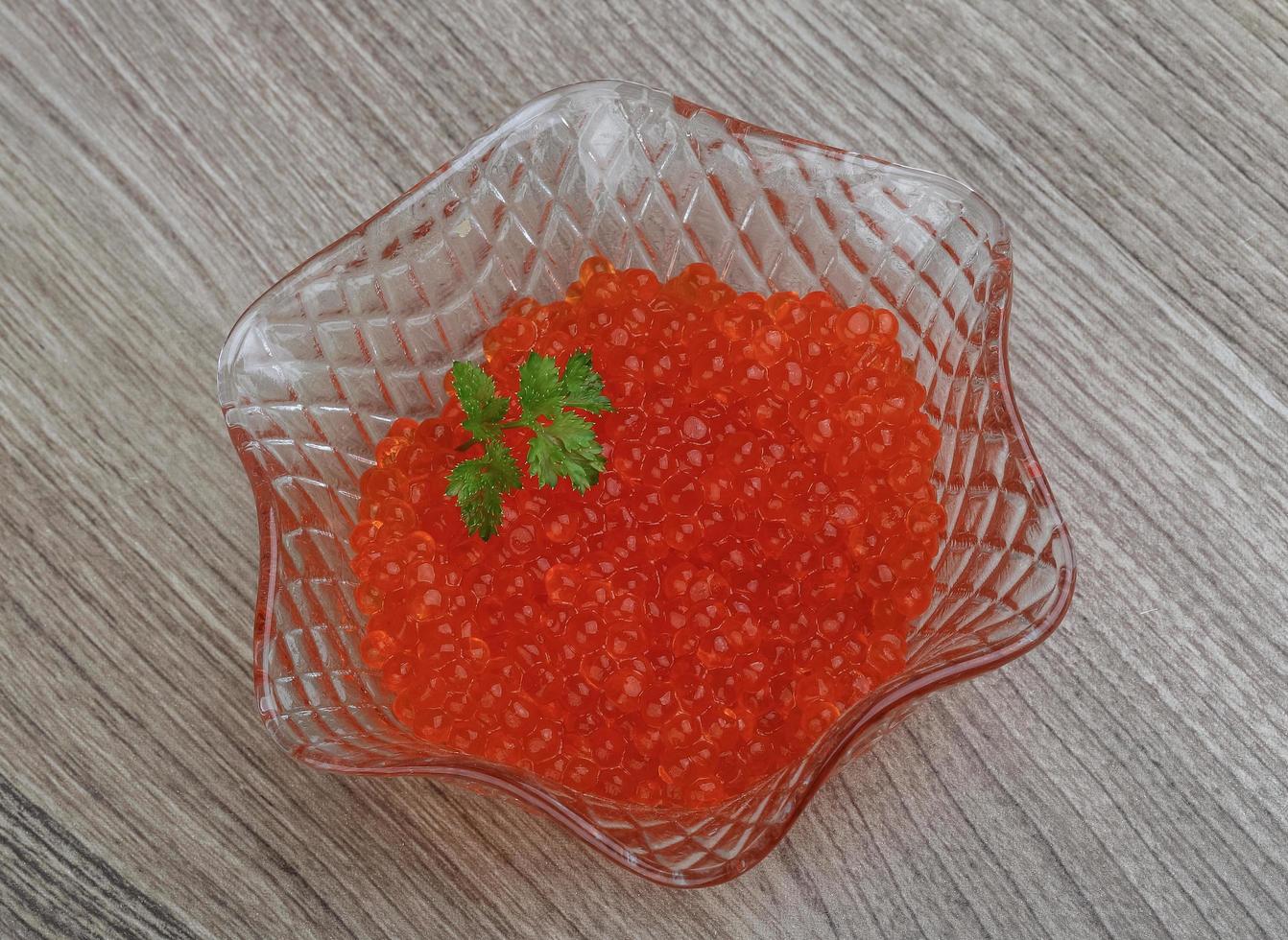 caviar vermelho em uma tigela sobre fundo de madeira foto