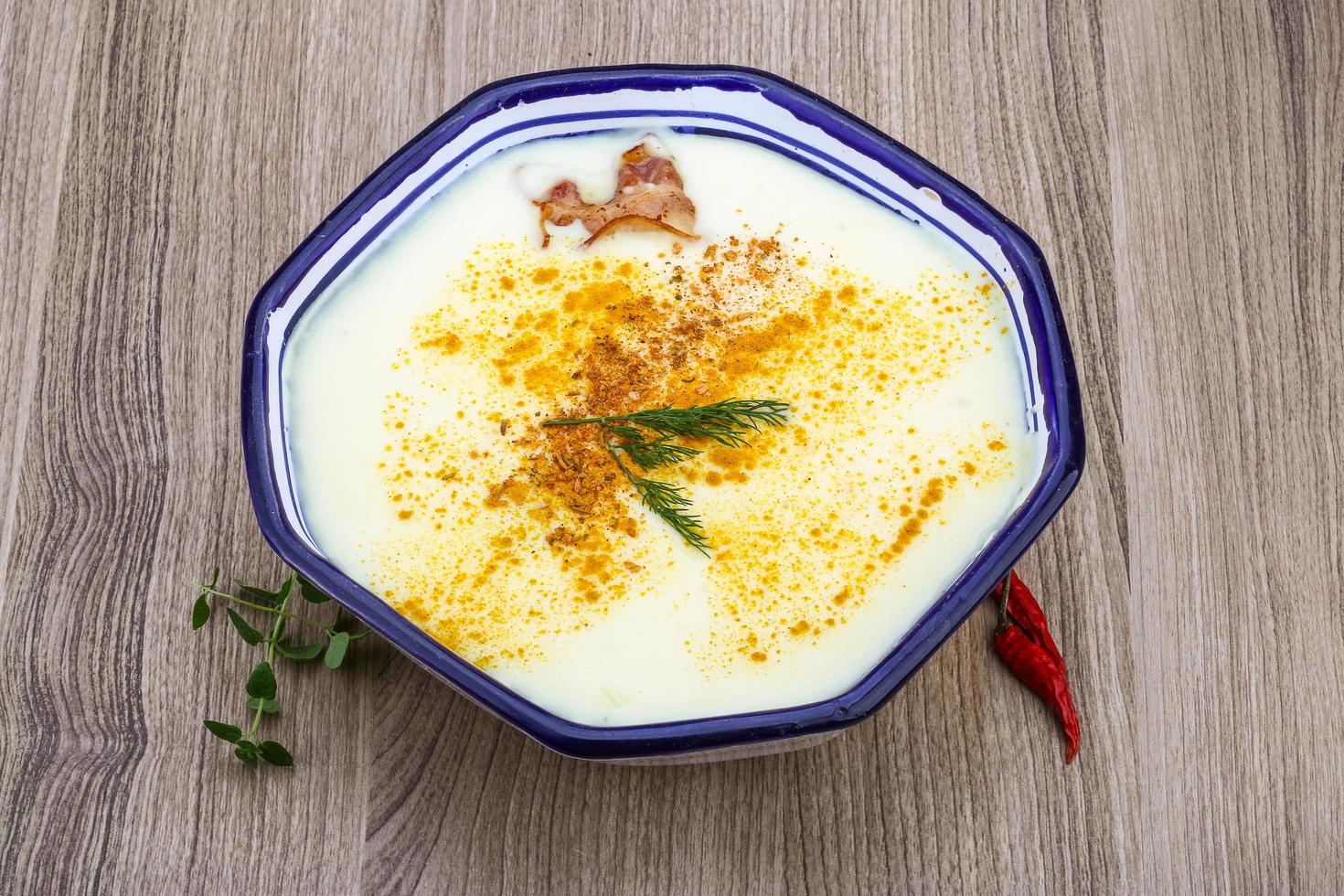 sopa de queijo em uma tigela com fundo de madeira foto