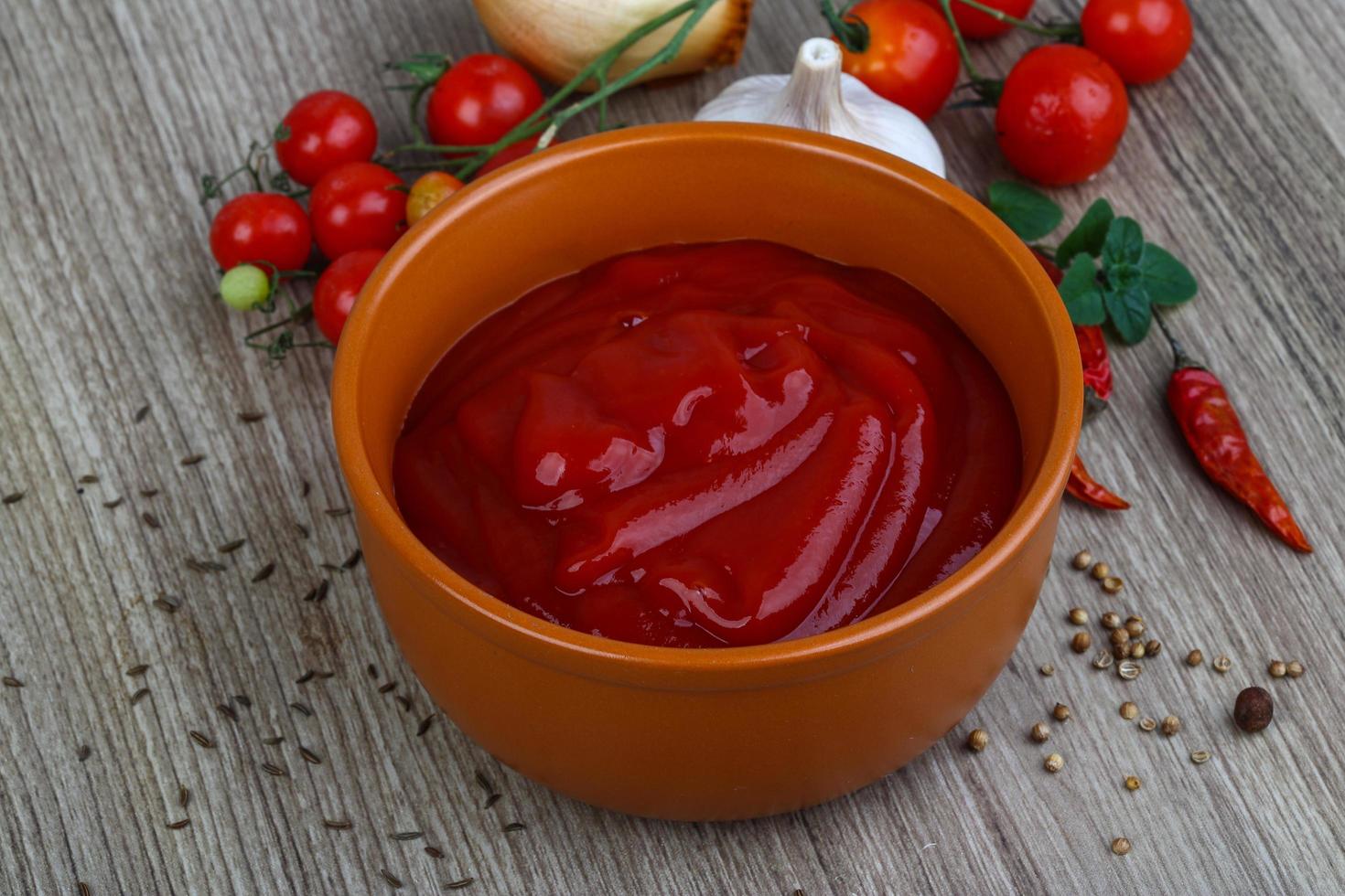 ketchup de tomate em uma tigela no fundo de madeira foto