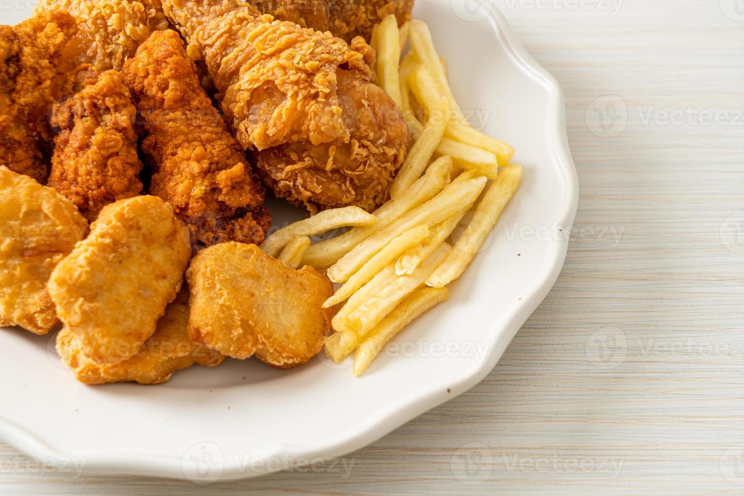 frango frito com batatas fritas e nuggets no prato foto