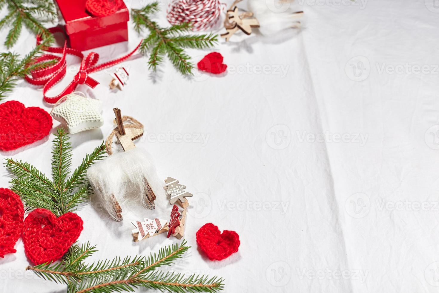 fundo de natal com caixas de presente, fita, barbante, rolos de papel, corações de malha e enfeite de natal. foto