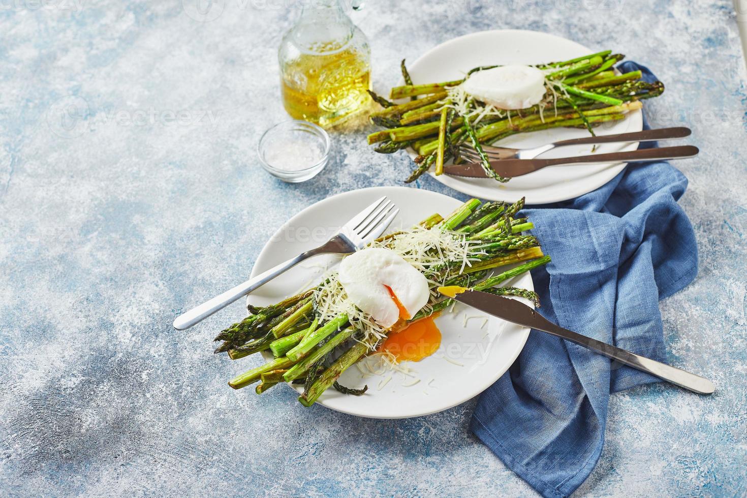 espargos verdes com ovo escalfado e parmesão, café da manhã vegetariano servido em dois pratos brancos foto