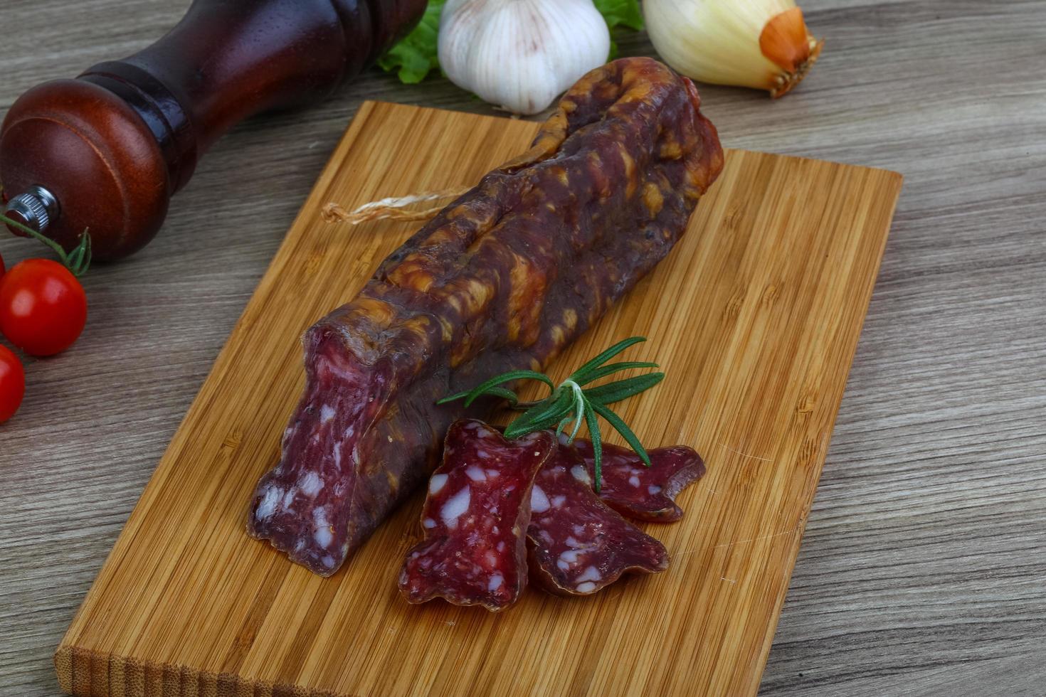 salsicha de salame na placa de madeira e fundo de madeira foto