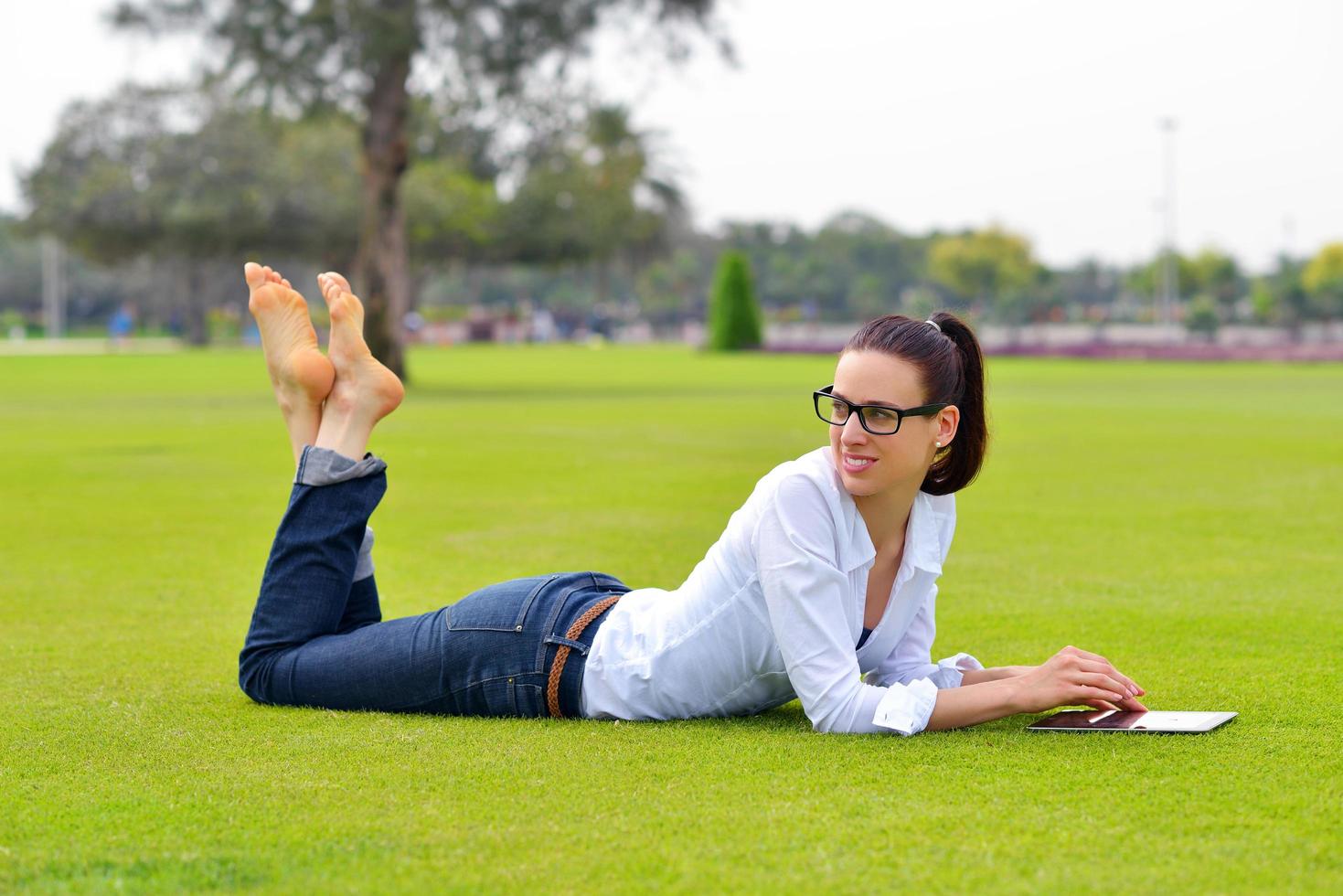 mulher jovem e bonita com tablet no parque foto