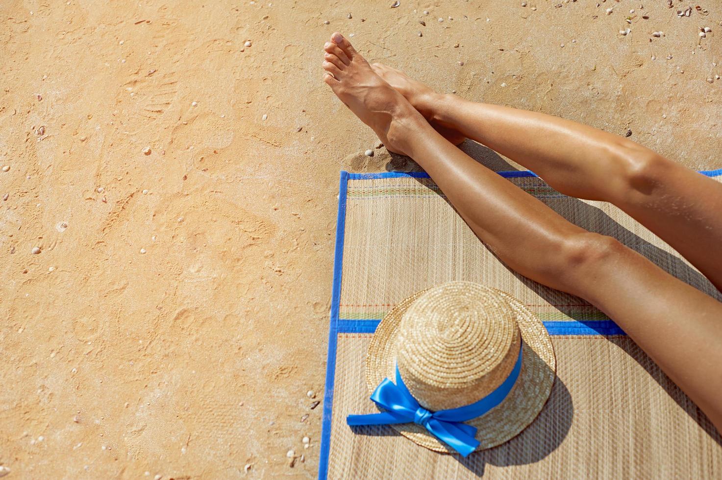 pés femininos e chapéu de palha na praia foto