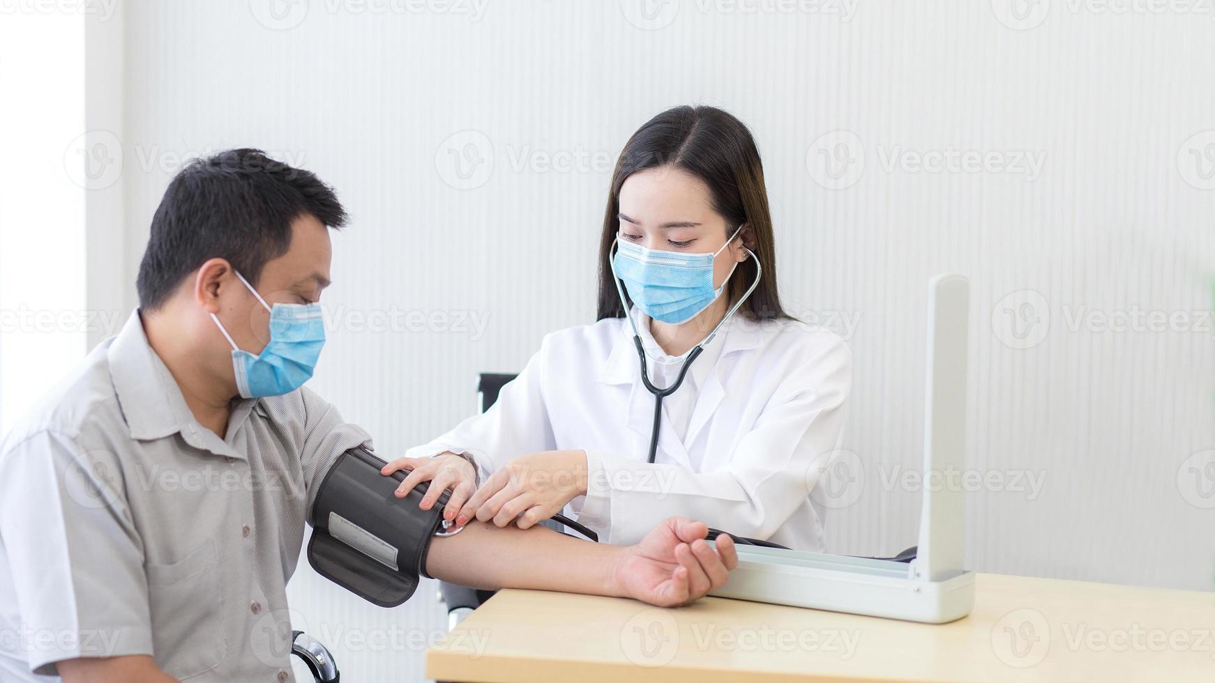 médica asiática mede a pressão arterial de um paciente homem usando um medidor de pressão arterial no hospital enquanto usa uma máscara facial médica para anti-infecção do sistema respiratório. foto