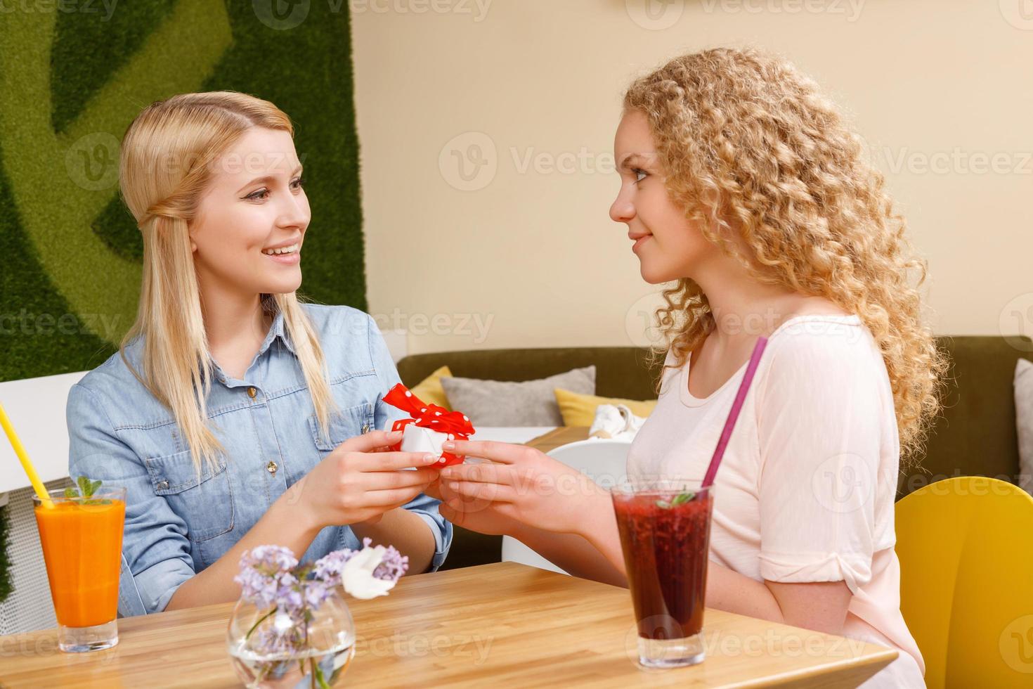 duas garotas dando presentes uma à outra no café foto