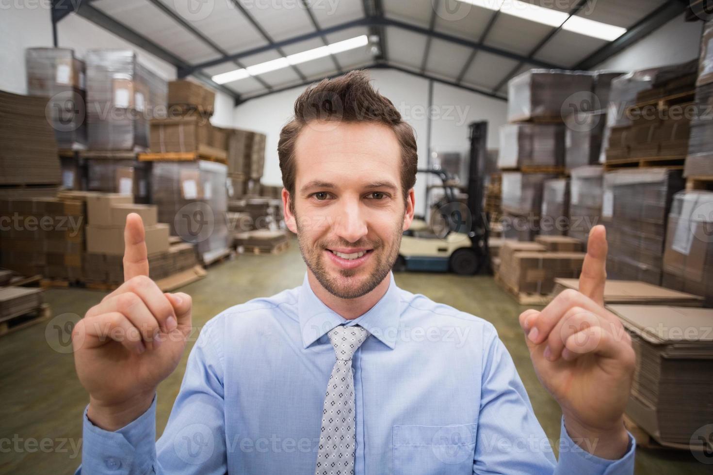 gerente de armazém sorridente apontando para cima com o dedo foto