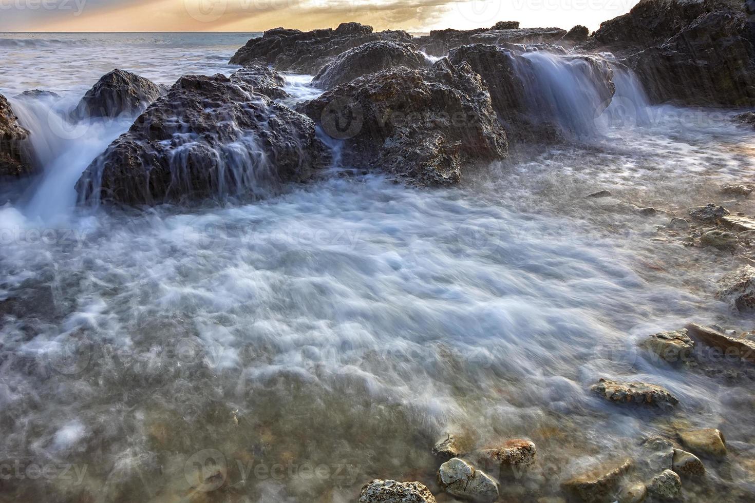 bela água do mar fluindo sobre as rochas. fechar-se foto