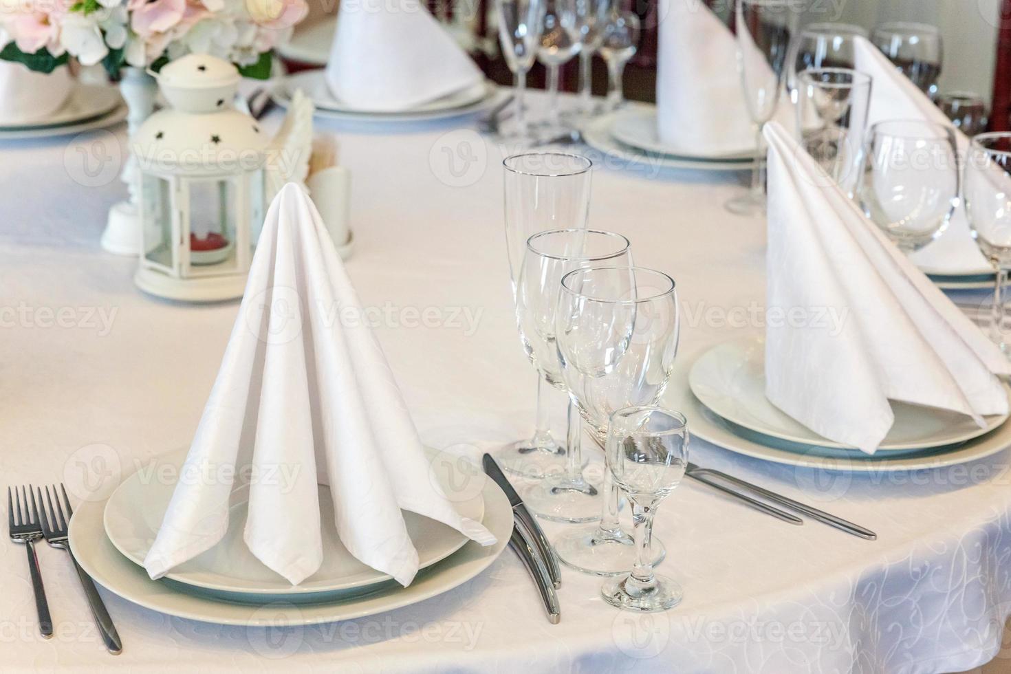 mesa chique para jantar com copos de guardanapo no restaurante, fundo interior de luxo. decoração de banquete elegante de casamento e itens para alimentos organizados pelo serviço de catering na mesa de toalha de mesa branca. foto