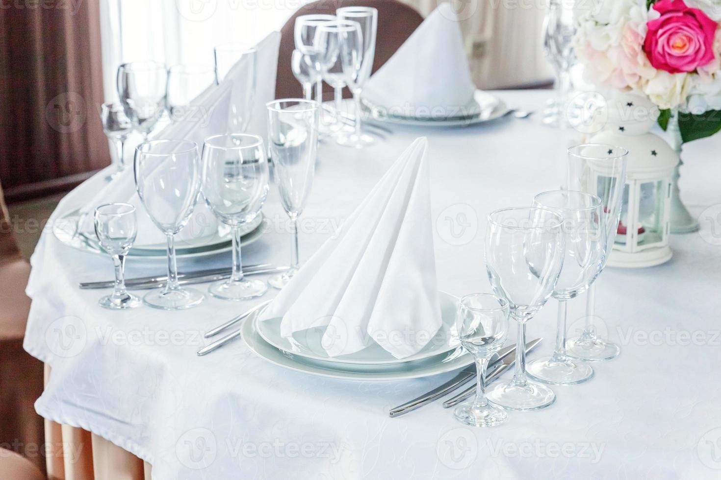 mesa chique para jantar com copos de guardanapo no restaurante, fundo interior de luxo. decoração de banquete elegante de casamento e itens para alimentos organizados pelo serviço de catering na mesa de toalha de mesa branca. foto