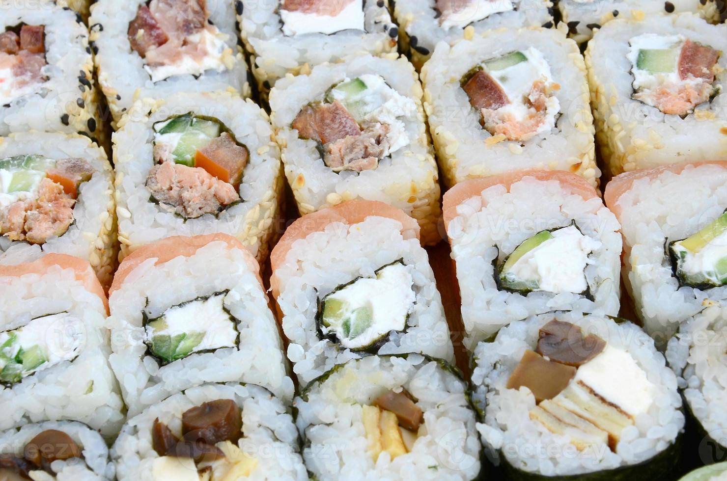 close-up de muitos rolos de sushi com recheios diferentes. tiro macro de comida japonesa clássica cozida. imagem de fundo foto