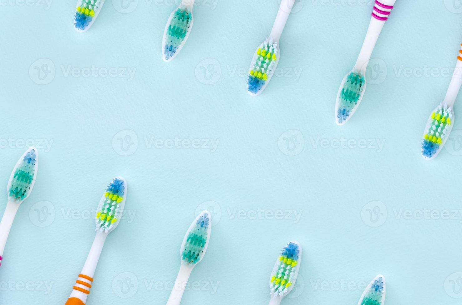 muitas escovas de dentes estão em um fundo azul pastel. vista superior, postura plana. conceito mínimo foto
