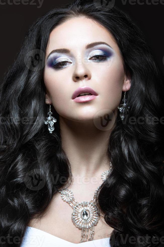 elegante menina bonita com maquiagem prata e cachos pretos. foto