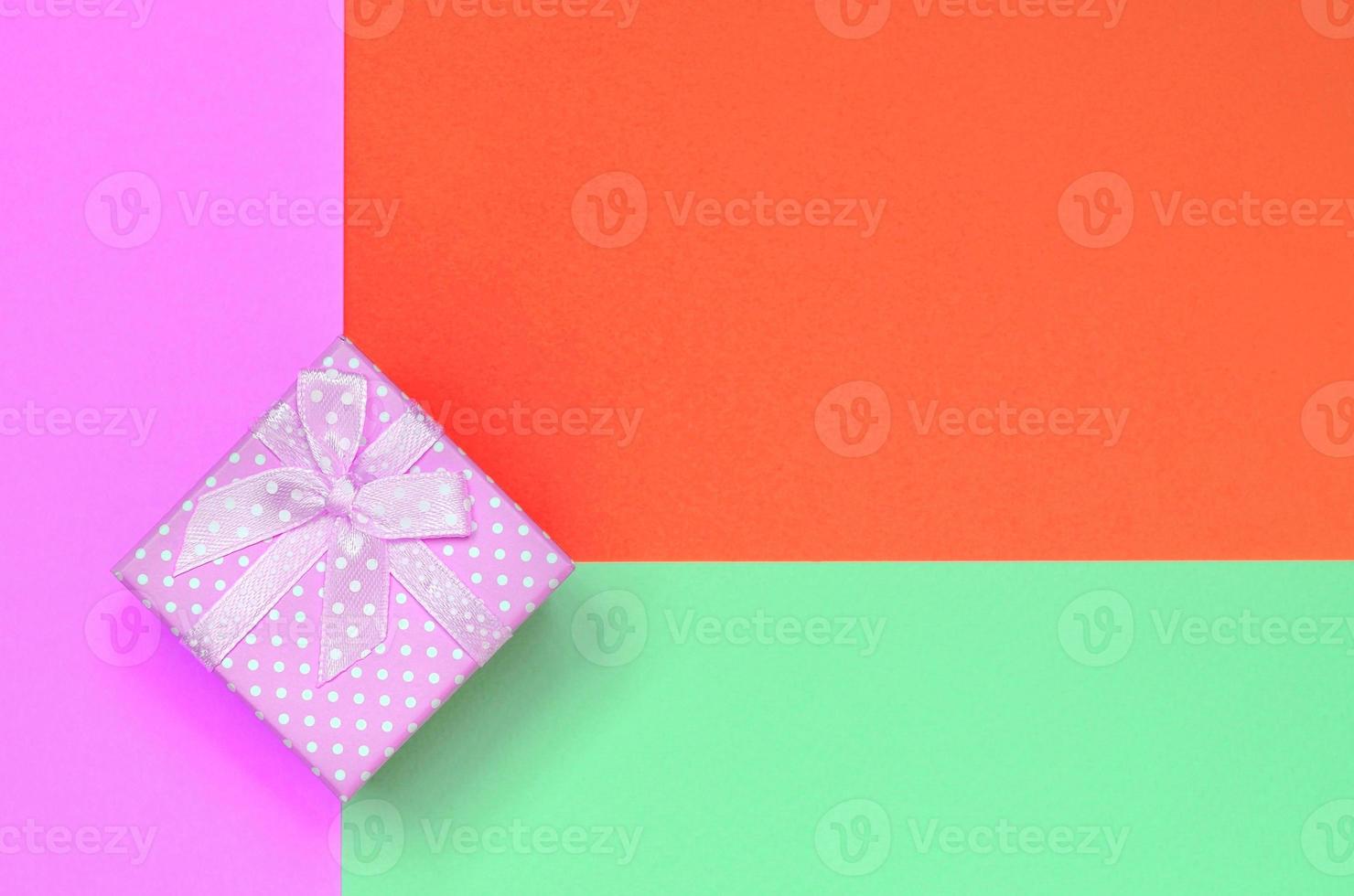 pequena caixa de presente rosa encontra-se no fundo de textura do papel de cores turquesa, vermelho e rosa pastel de moda foto