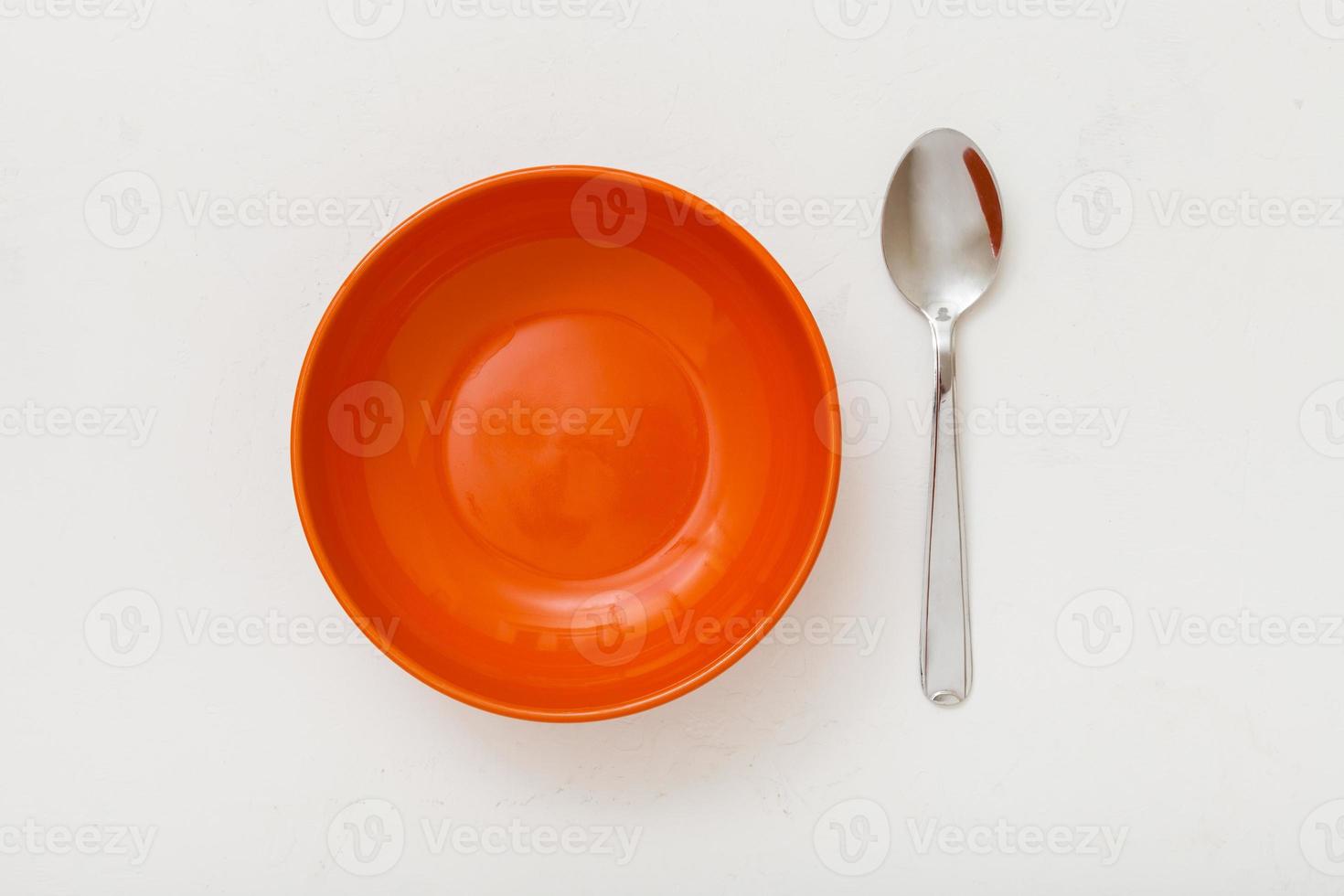 vista superior da tigela laranja e colher em gesso branco foto