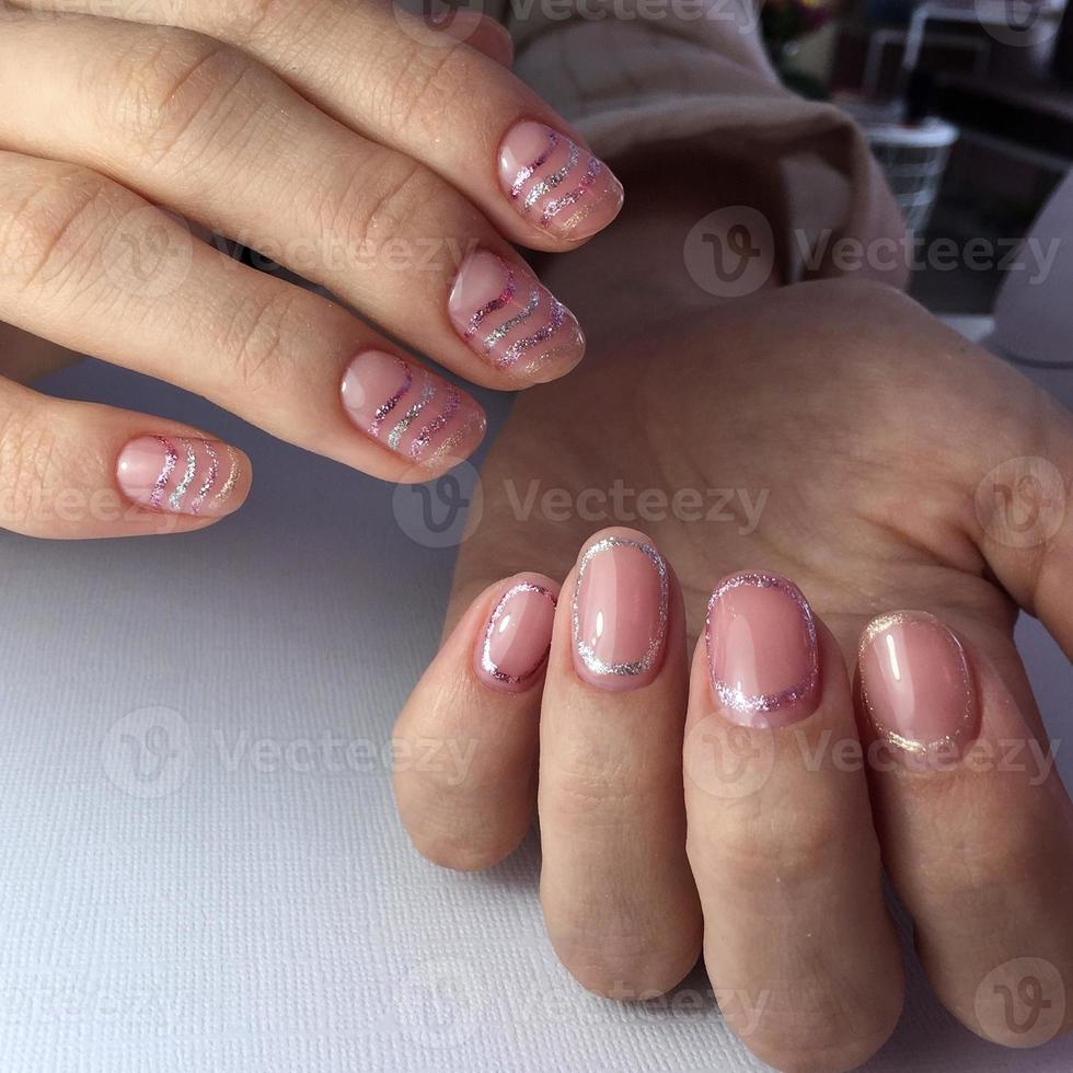 mãos femininas com manicure rosa elegante em fundo branco foto