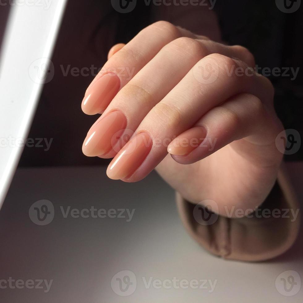 mãos femininas com manicure rosa elegante em fundo branco foto